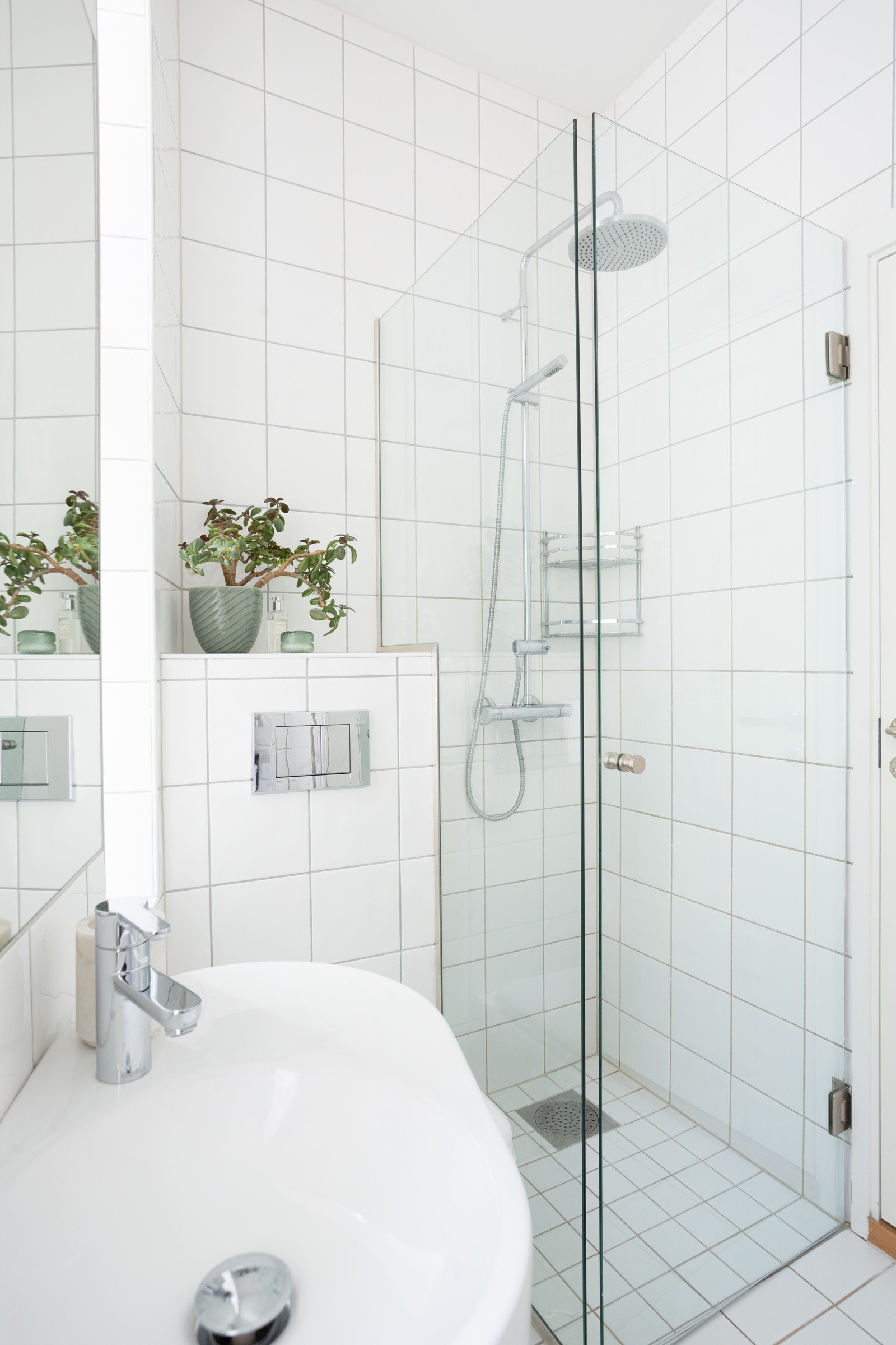 Videre er badet utstyrt med vegghengt wc og servant dusj i hjørne med glassdør/veggdører. Galleribilde