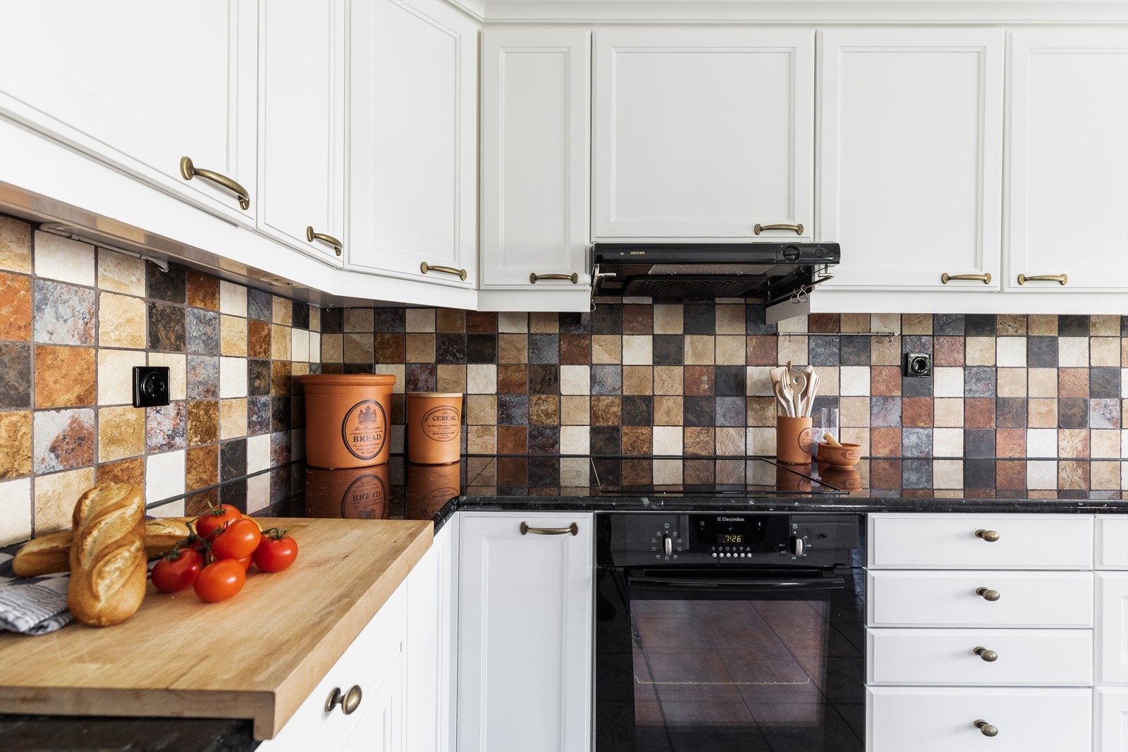 Den har lekker granittbenkeplate i larvikitt, profilerte fronter, nedfelt keramisk kokeplate, integrert ovn og ventilator med avtrekk ut i vegg Galleribilde