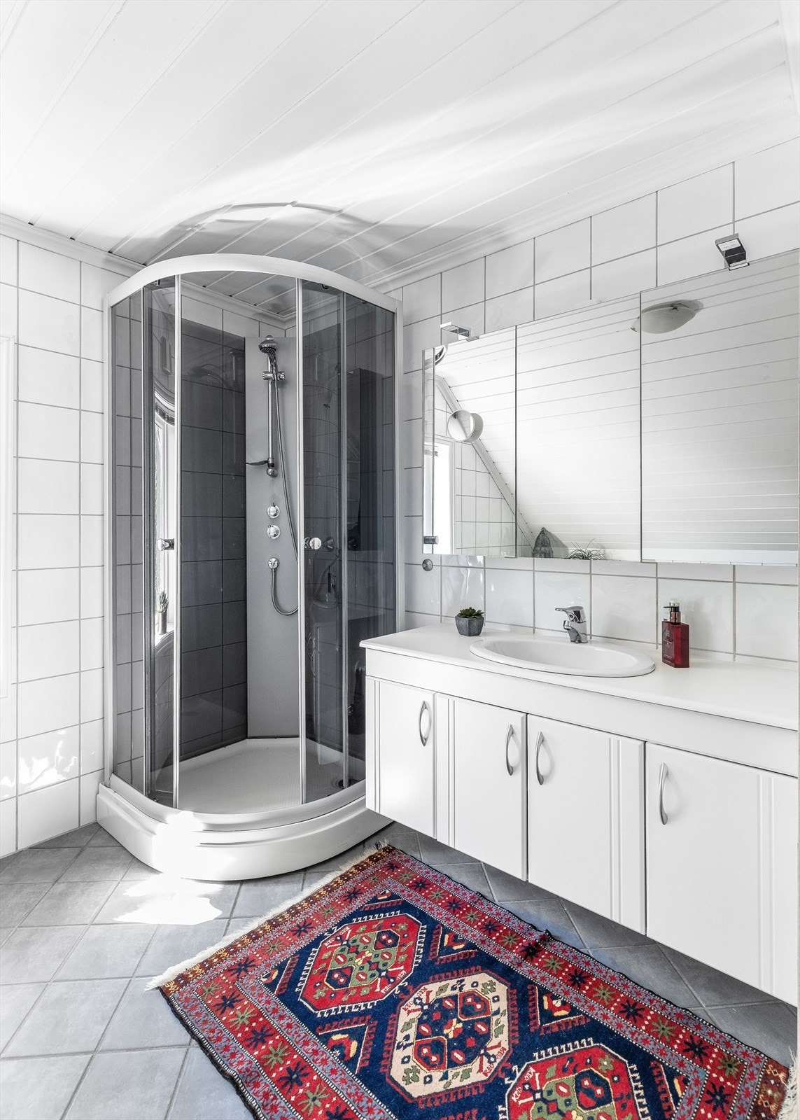 Badet inneholder servantskap og hvit benkeplate med nedfelt vask og rillete fronter Galleribilde