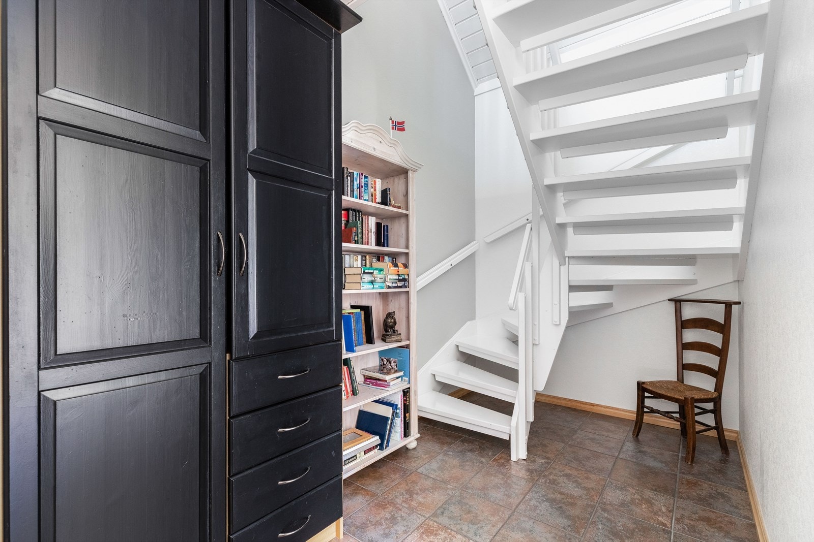 Fra gangen går det en åpen hvitmalt tretrapp til andre etasje Galleribilde