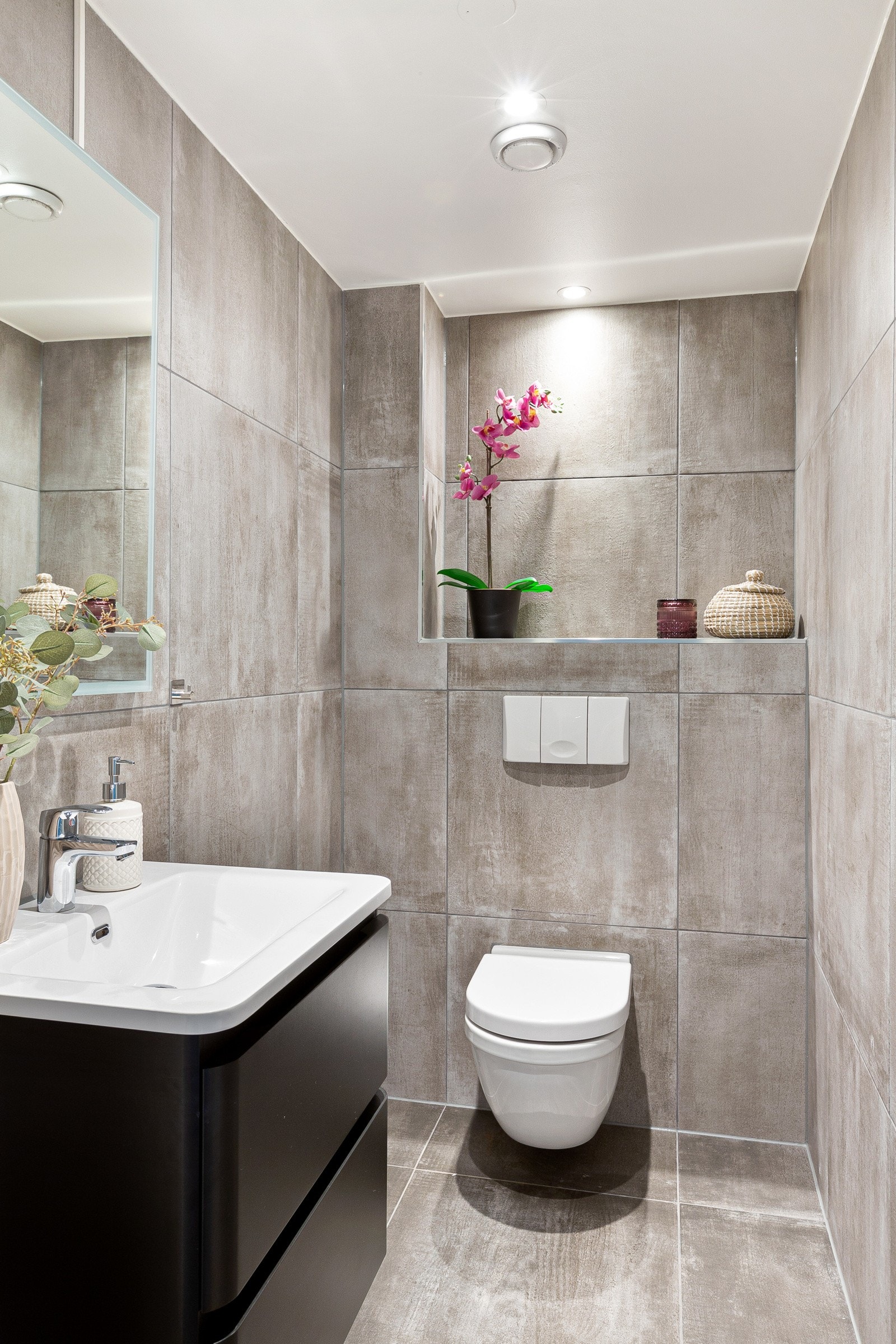 I likhet med badet har også toalettrommet flislagte gulv og vegger, samt gulvvarme. Her har du et vegghengt servantskap, vegghengt toalett og speil med belysning over servant Galleribilde