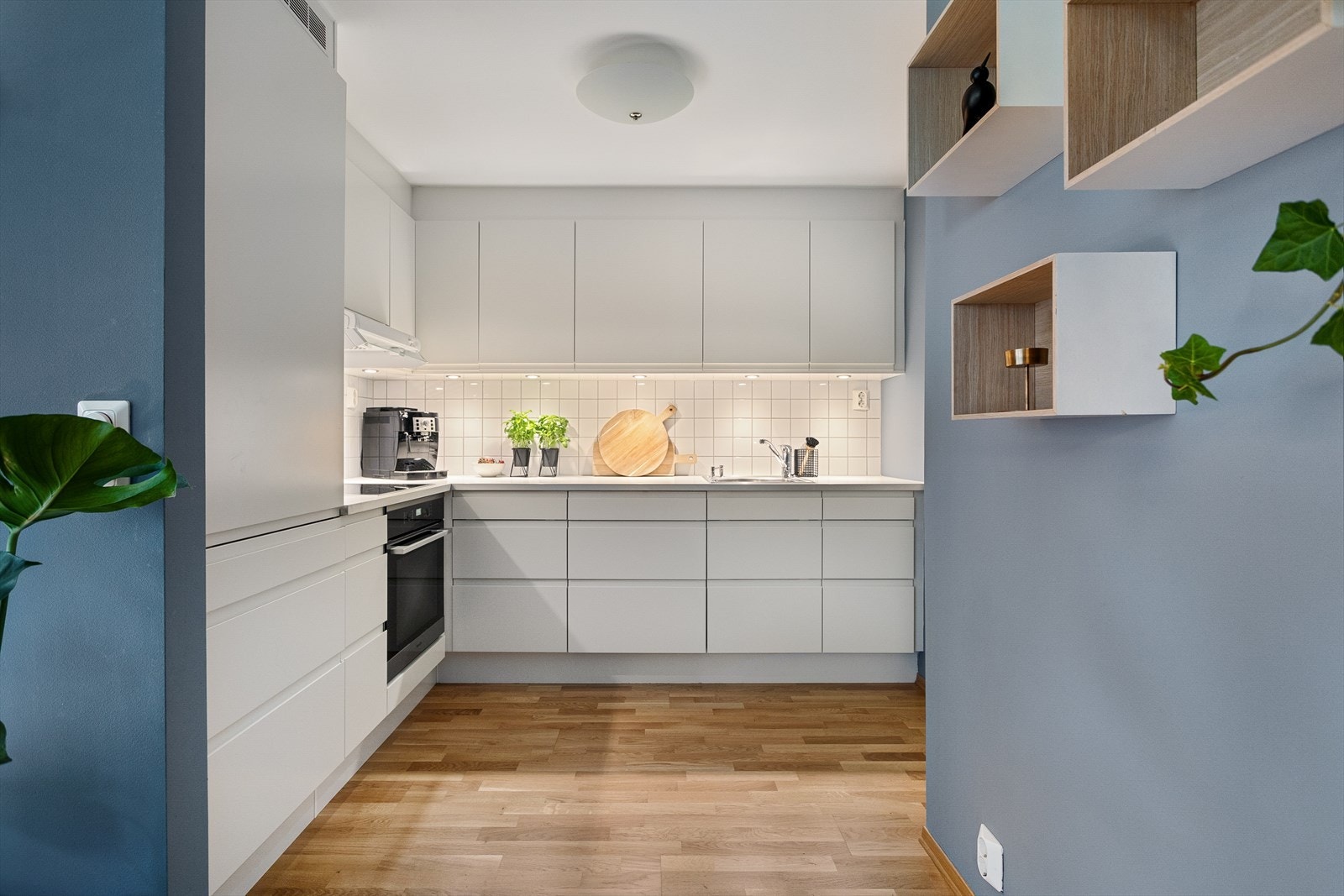Stilrent og moderne HTH kjøkken med hvite profilerte fronter, benkeplate av laminat og nedfelt oppvaskkum i rustfritt stål med ett-greps armatur. Galleribilde