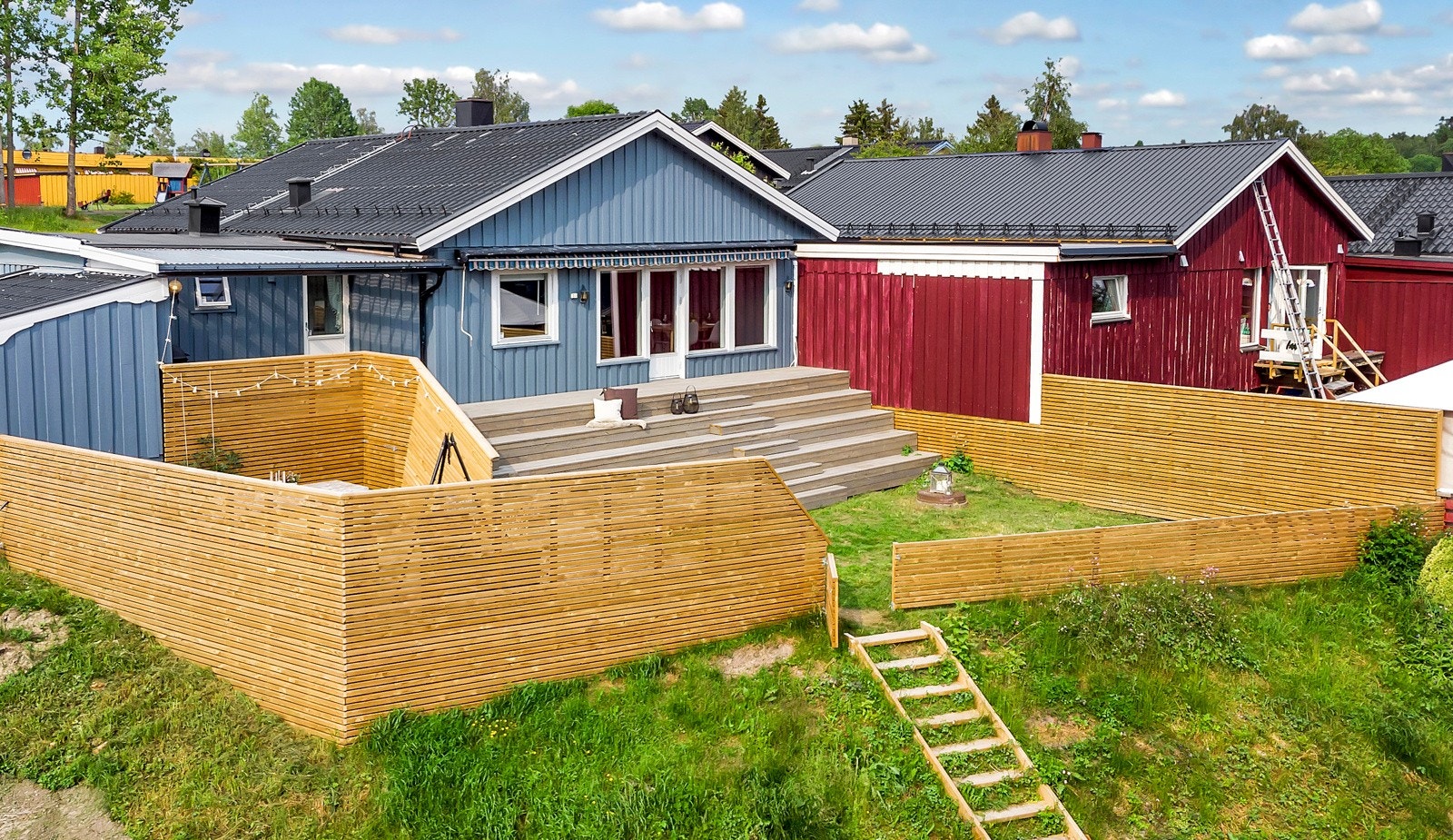 Tomten er pent opparbeidet med terrasseplatting, gressplen og gjerde med port. Galleribilde