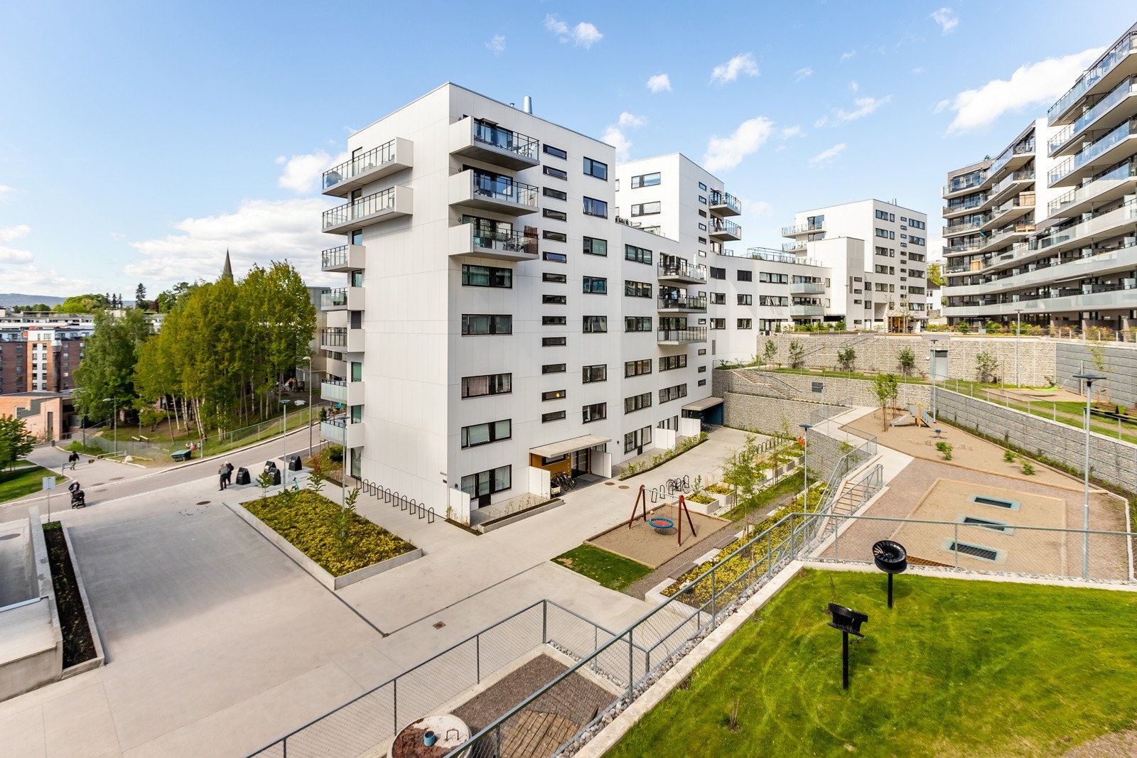Fasaden med borettslagets flotte, opparbeide uteområder med lekeplasser, sittegrupper m.m. i forgrunnen. Galleribilde