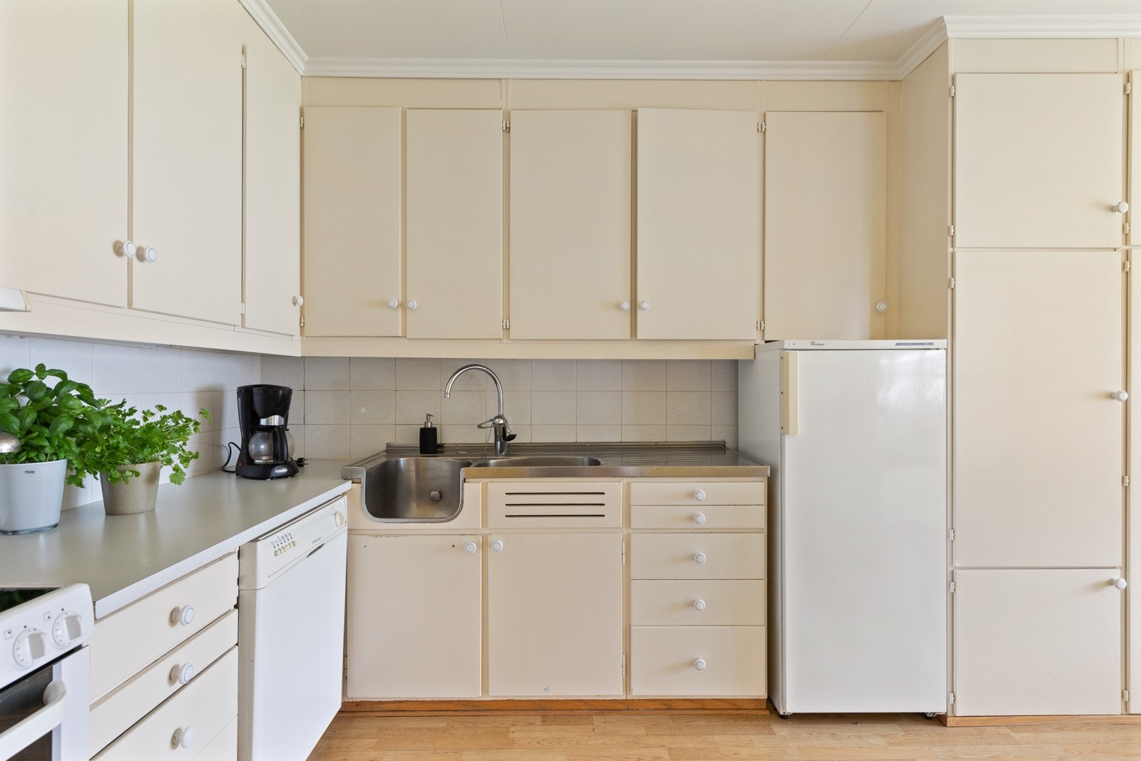 Kjøkkeninnredningen er plassbygget, har slette fronter og laminert benkeplate. Det er lagt fliser på vegg under overskap. Galleribilde