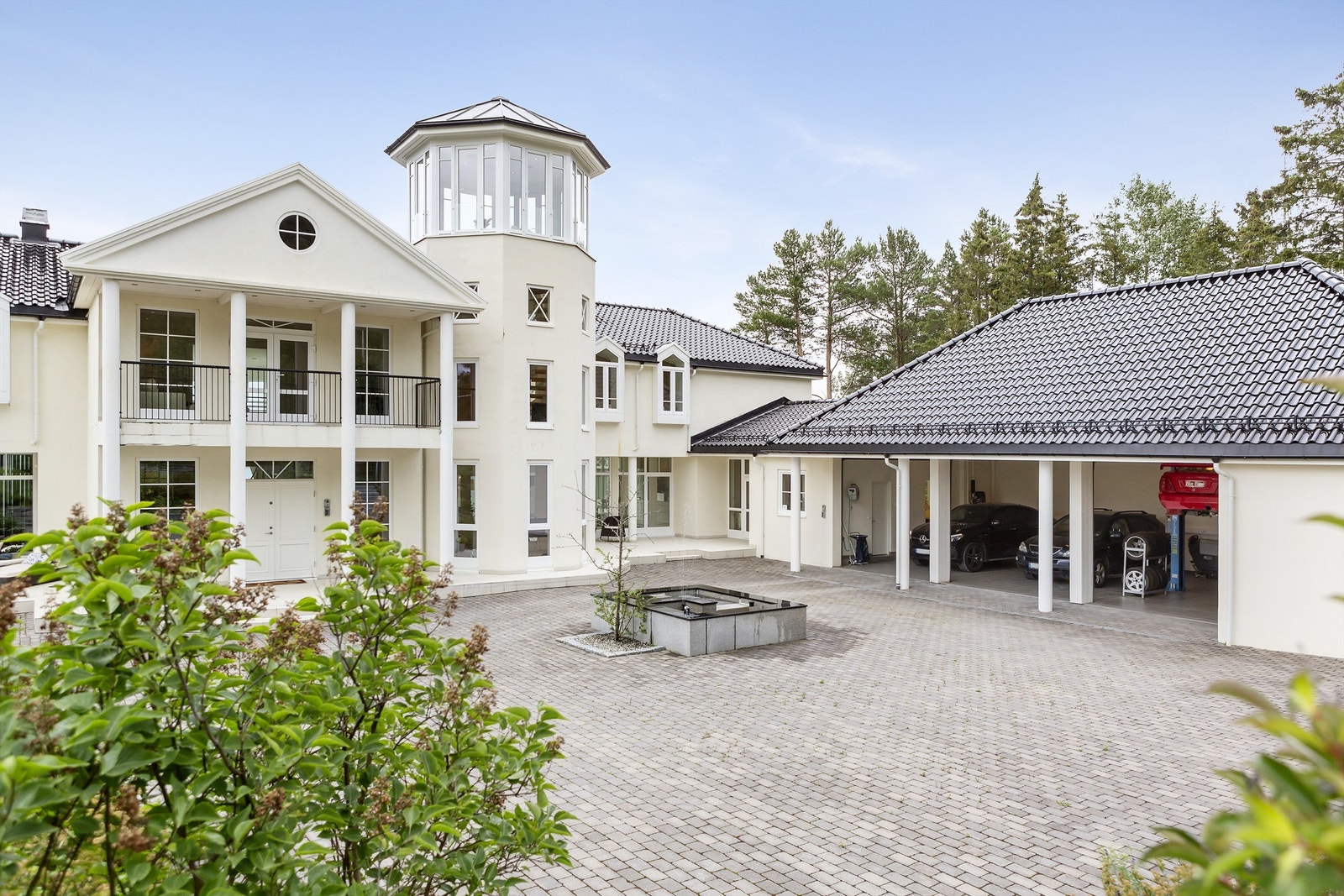 Eiendommen har trippelgarasje og stor, steinsatt gårdsplass med adkomst via en pent anlagt allé. Galleribilde