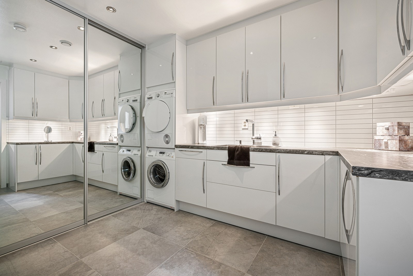 Videre har boligen et praktisk separat vaskerom. Innredningen består av utslagsvask i benkeplate, samt mye oppbevaringsplass med høyglansfronter. Røropplegg for både vaskemaskin og tørketrommel. Galleribilde