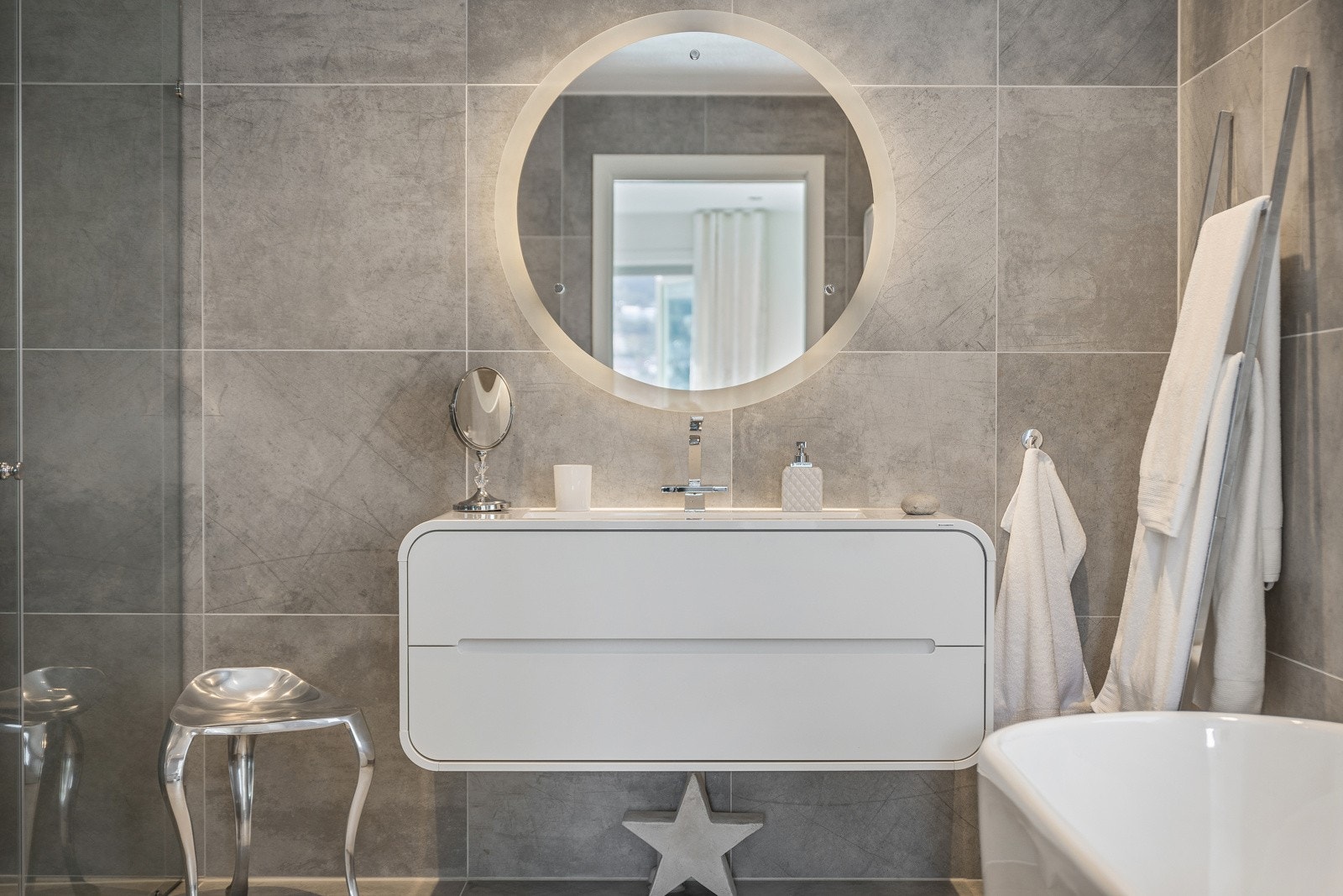 Hovedbadet er helfliset med keramiske fliser. Innredningen består av vegghengt toalett, dusj og servant med møblement, speil og belysning. Galleribilde