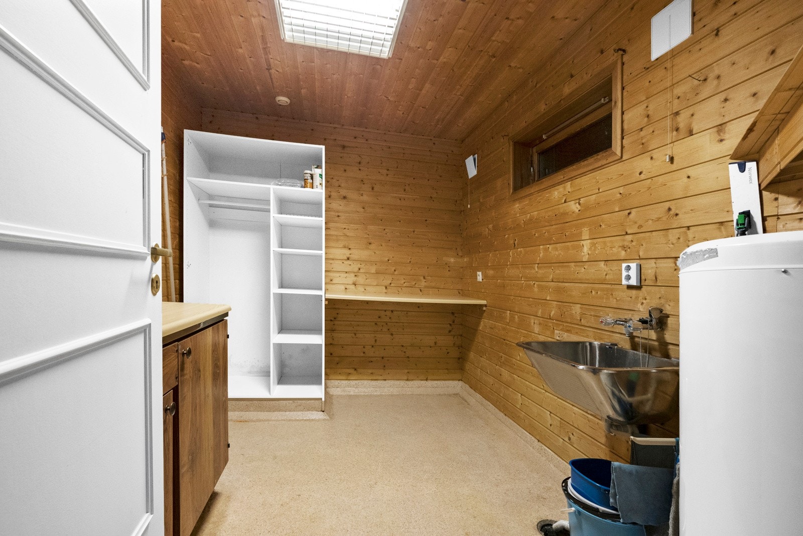 Vaskerommet i underetasjen. Rommet er innredet med vegghengt utslagsvask av stål, høyskap, hylleløsning og opplegg for vaskemaskin. Praktisk plassering nært hovedinngangen. Galleribilde