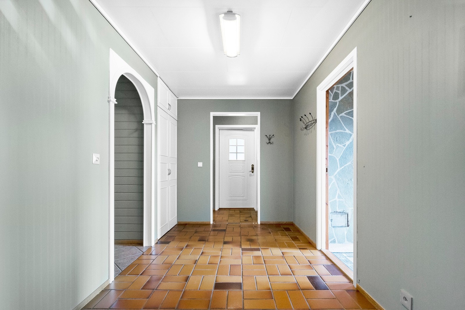 Du entrer boligen inn i en romslig og avlang gang, med tilgang til hele underetasjen. Galleribilde