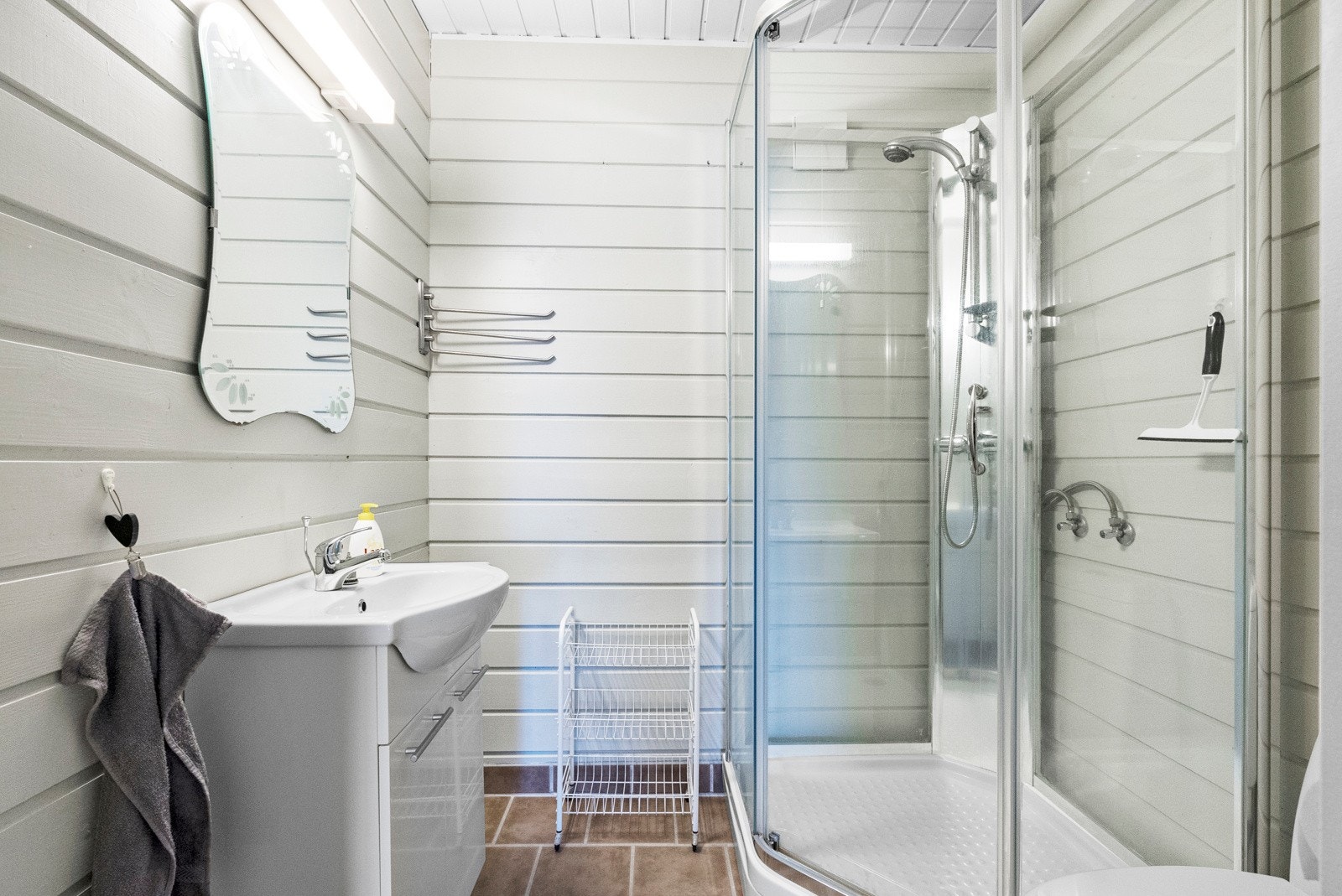 Dette er badet i underetasjen. Rommet er i dag innredet med servant med underskap, veggspeil, dusjkabinett og frittstående toalett. Galleribilde