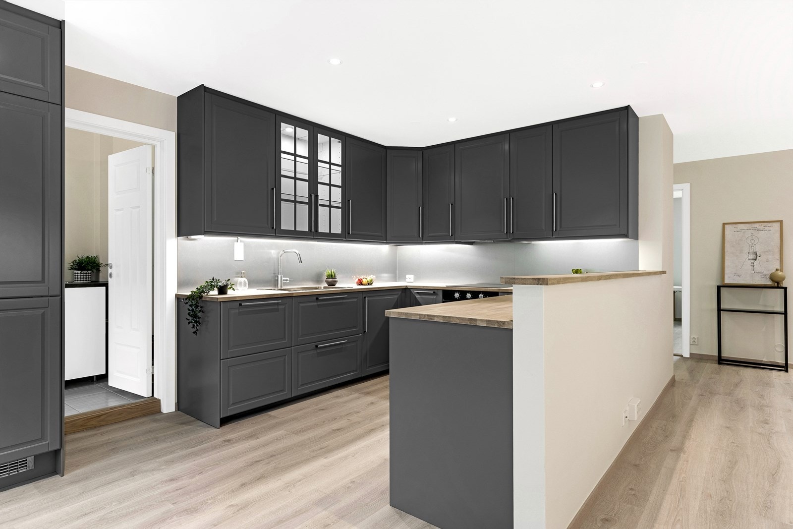 Kjøkkeninnredning med profilerte fronter. Enkelte glassfronter og belysning i overskap. Lyslister og belysning under overskap. Galleribilde