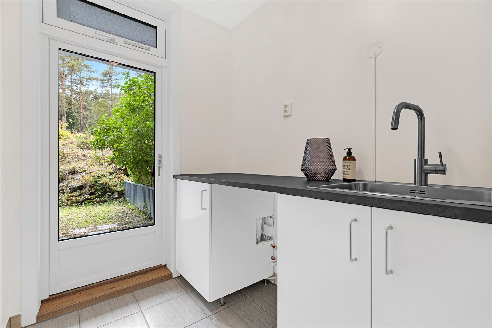 Innredning bestående av benkeskap med glatte fronter. Laminat benkeplate med nedfelt kum i rustfritt stål. Nedfelt kum i rustfritt stål og opplegg for vaskemaskin. Galleribilde