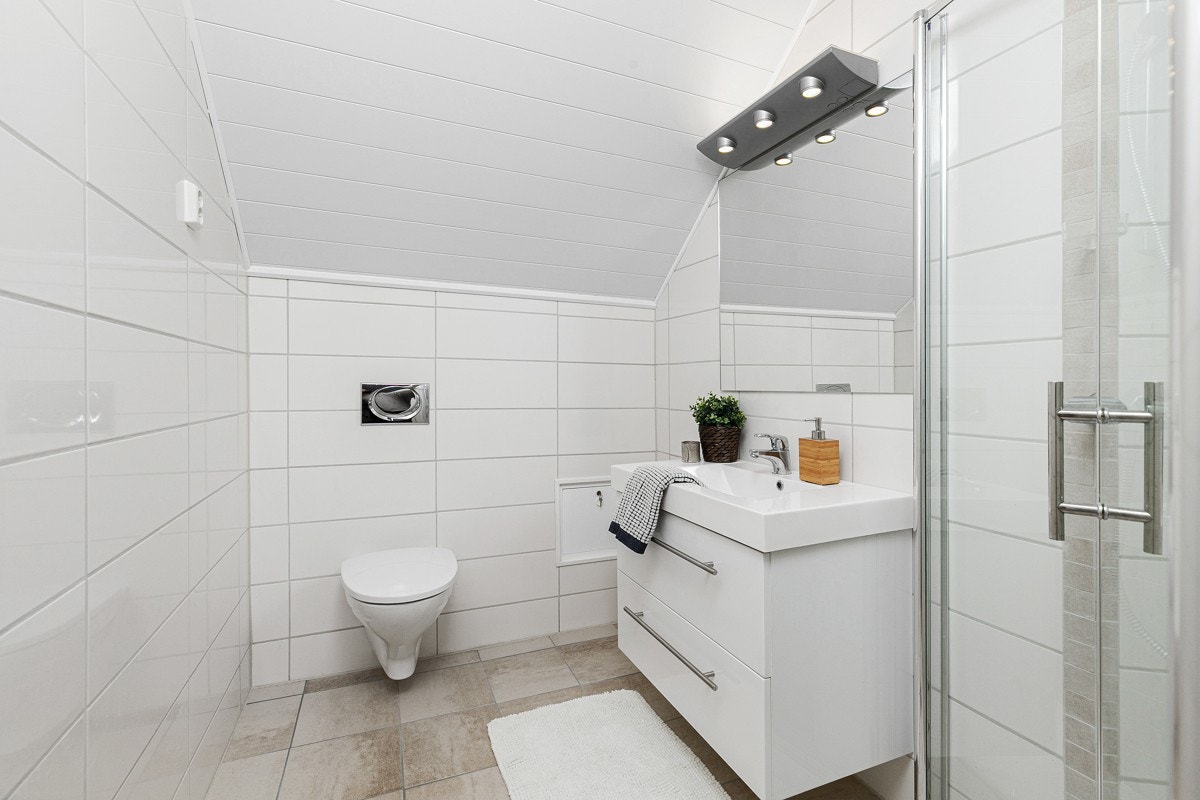 Badet i tredje etasje er delikat innredet med hvite veggfliser og jordfargede gulvfliser over gulvvarme. Galleribilde