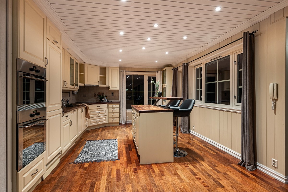 Stirent kjøkken med funksjonell utforming og en sosial kjøkkenøy med barløsning. Galleribilde