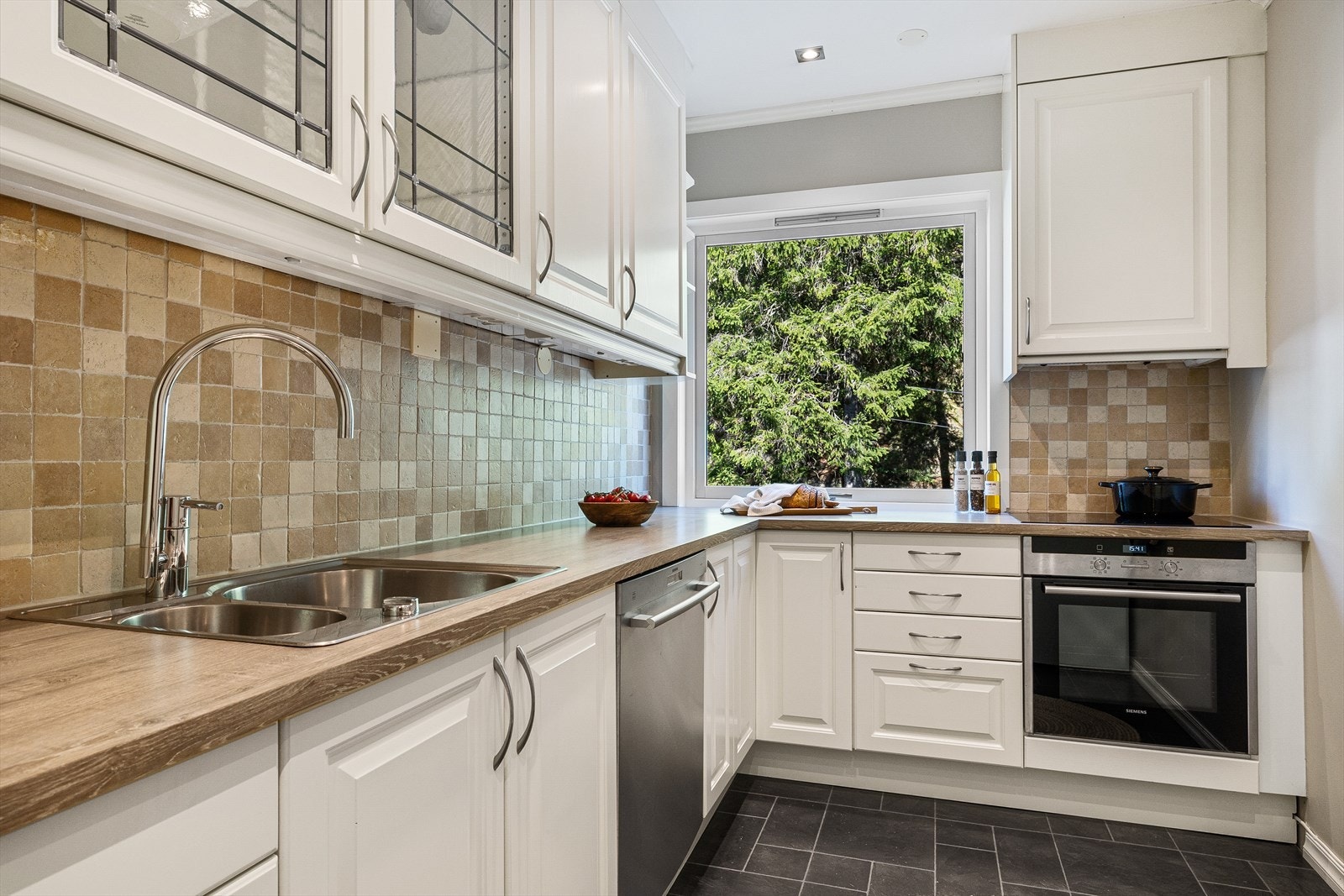 Fin kjøkkeninnredning fra 2007 med profilerte, hvite fronter og laminert benkeplate. Integrert induksjonsplatetopp og stekeovn (stekeovn fra 2021) Galleribilde