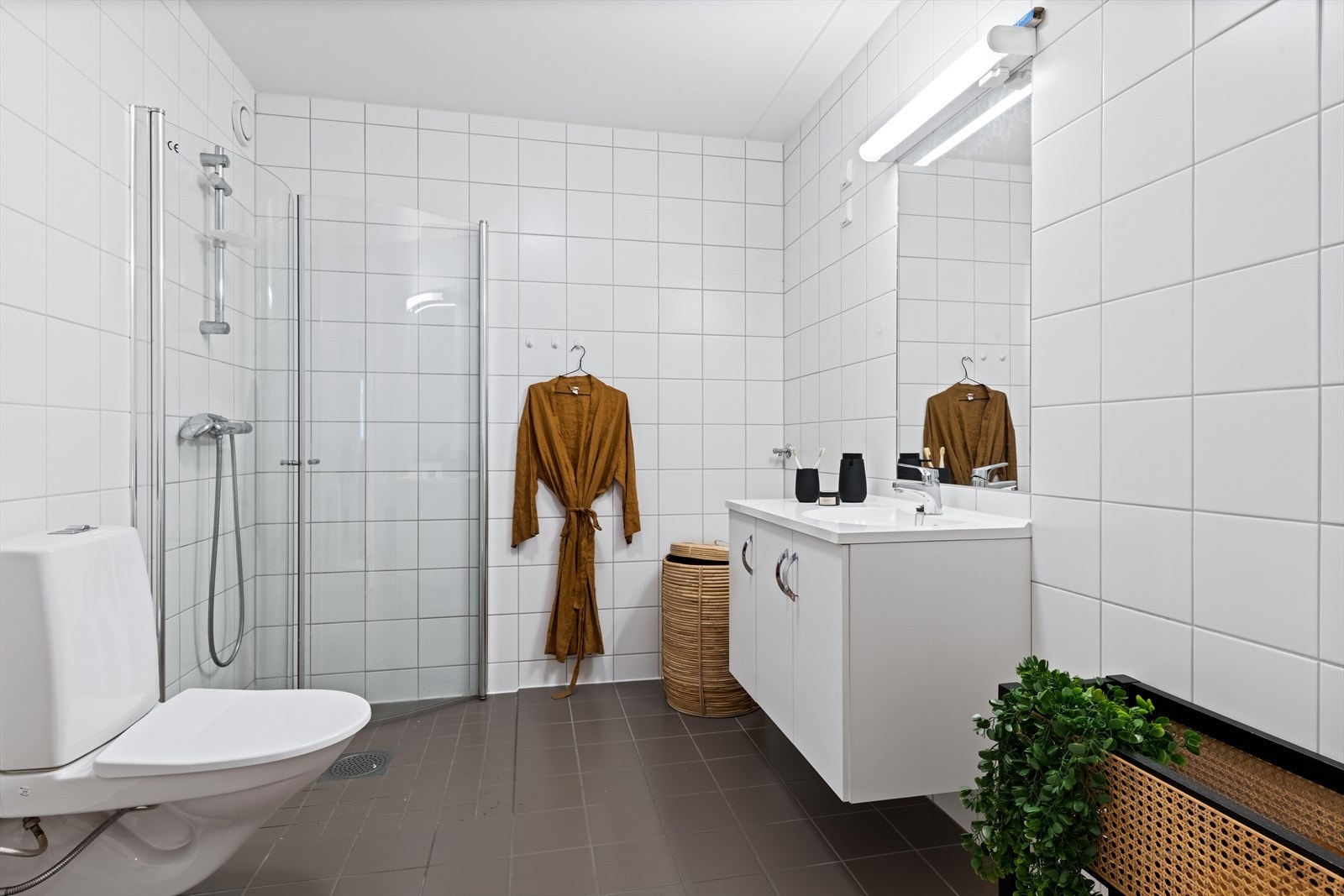 Pent flislagt baderom fra byggeårene med termostatstyrte varmekabler i gulv og opplegg for vaskemaskin. Galleribilde