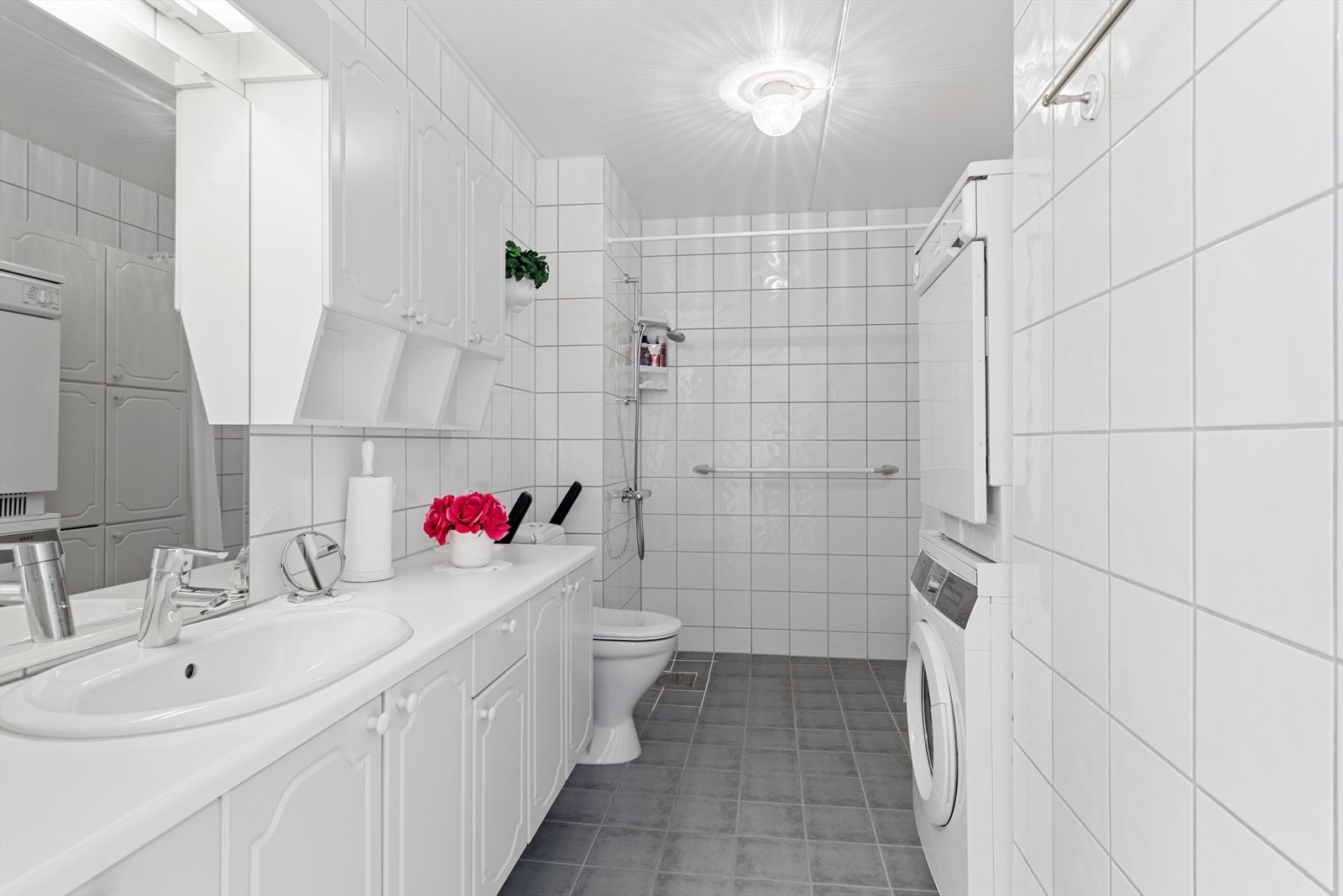 Baderomsinnredningen består blant annet av en servant med underskap og skuffer. Over servanten er det speil og belysning. Videre har man et gulvstående toalett, dusjhjørne og opplegg for vaskemaskin m.m. Galleribilde