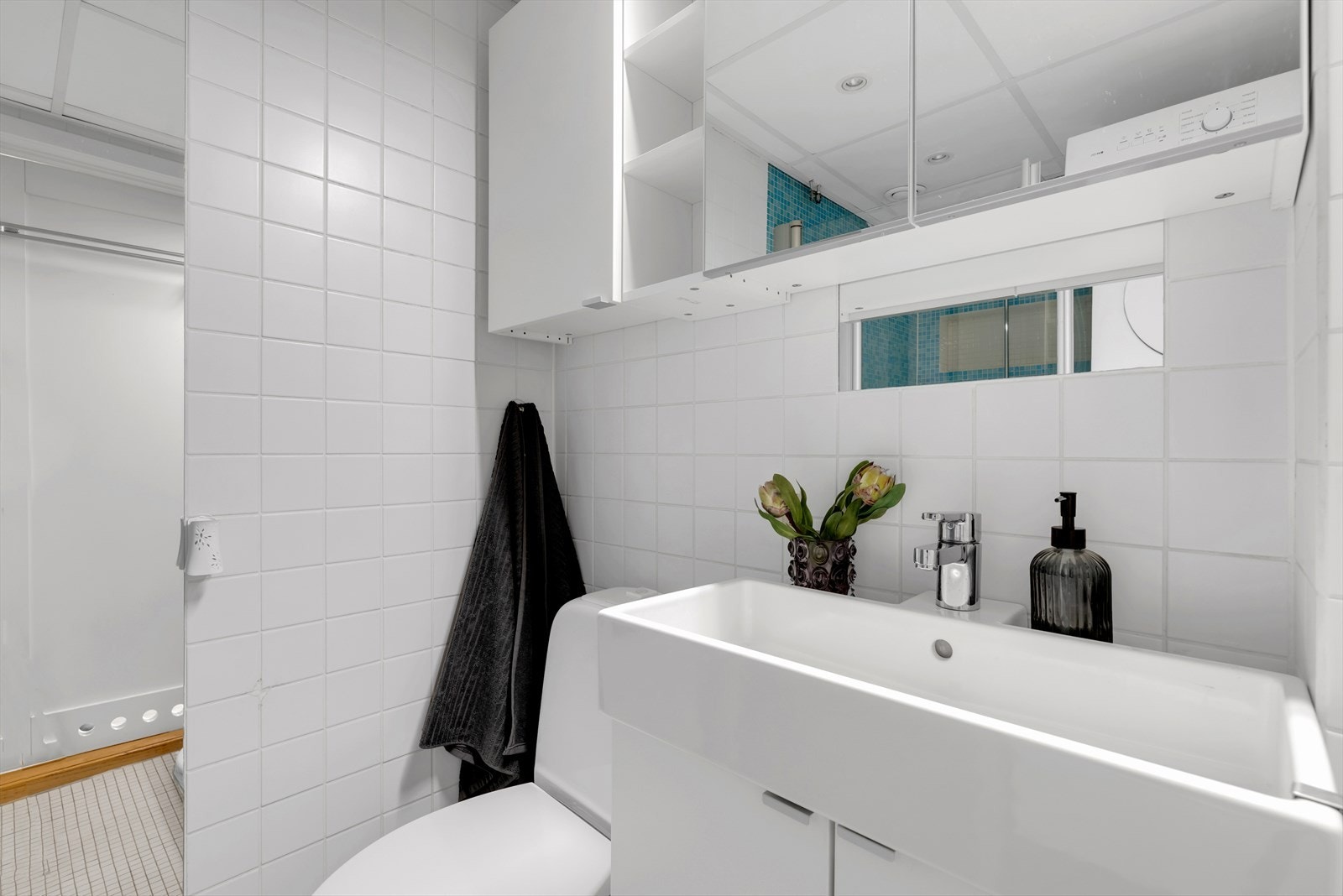 Badet er innredet med servant med underskap, speil, vaskemaskin og tørketrommel, wc og dusjhjørne med glassdører. Galleribilde