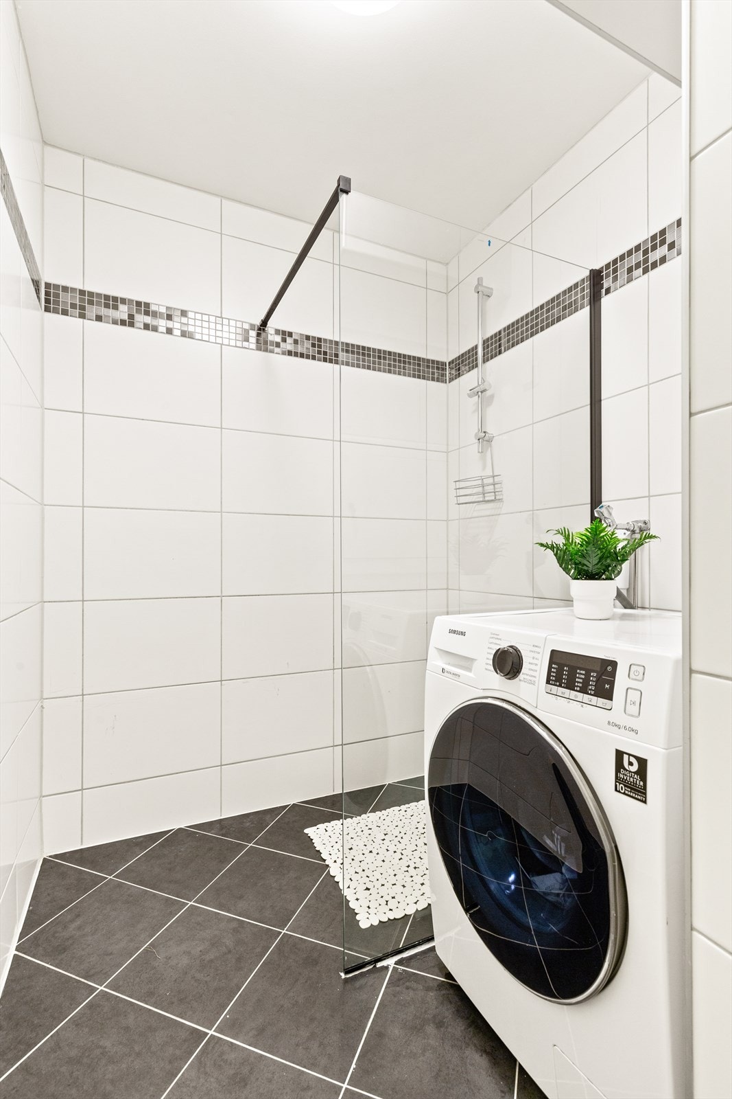 Badet er utstyrt med veggmontert dusjvegg og og opplegg for vaskemaskin. Galleribilde