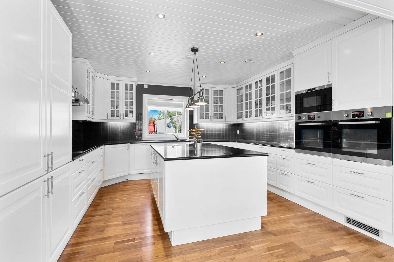 Innredningen har hvite, profilerte fronter, vitrineskap og benkeplate i stein. Galleribilde