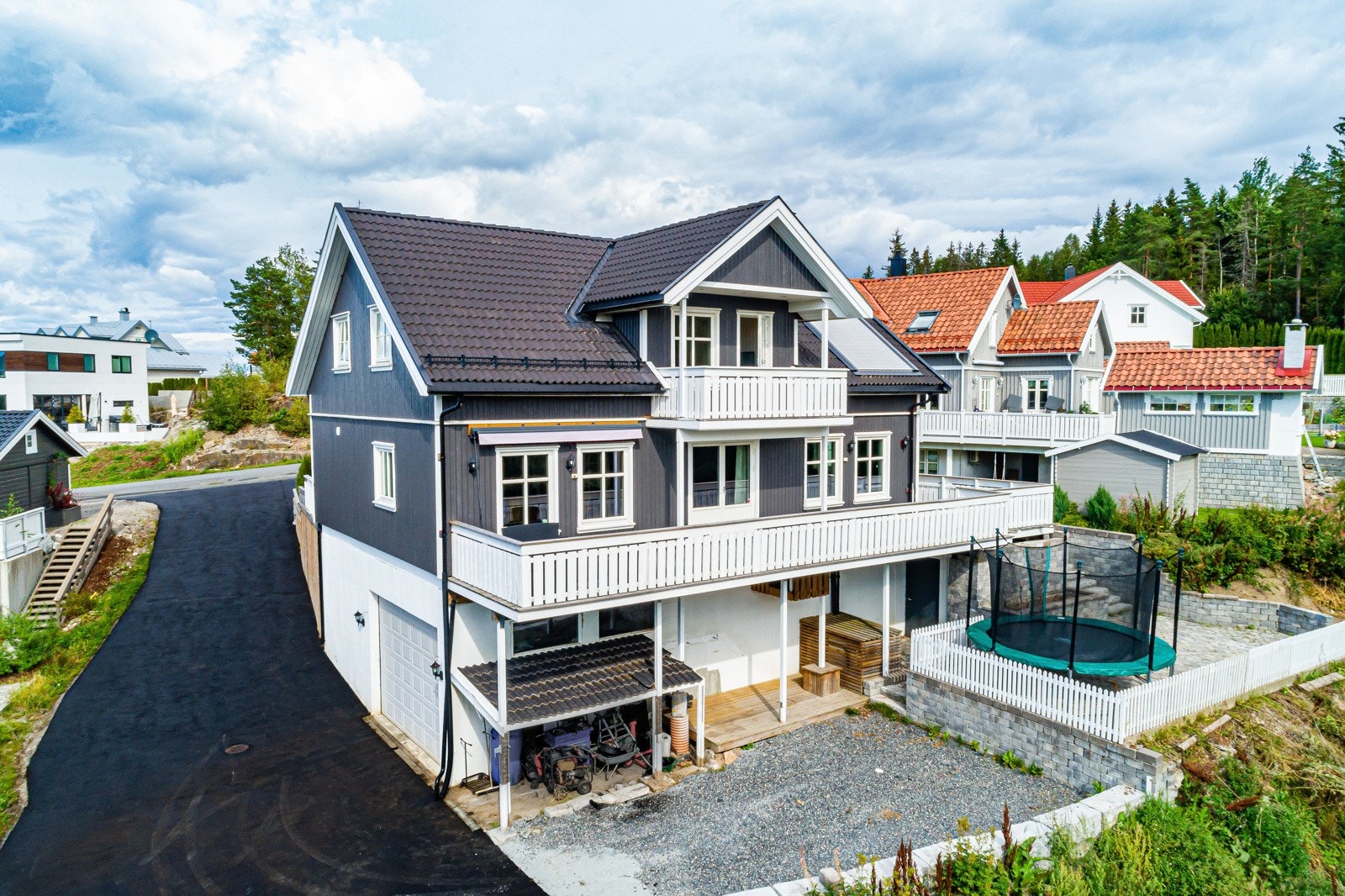 Eneboligen ligger på en romslig, delvis inngjerdet tomt, opparbeidet med plata•er og trapper i stablet stein. Galleribilde