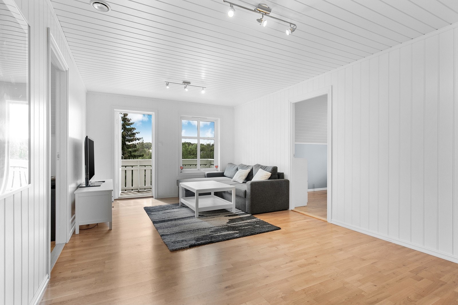 I andre etasje er det en lys, pen stue med parkettgulv, gulvvarme og hvitmalt smartpanel på veggene. Galleribilde