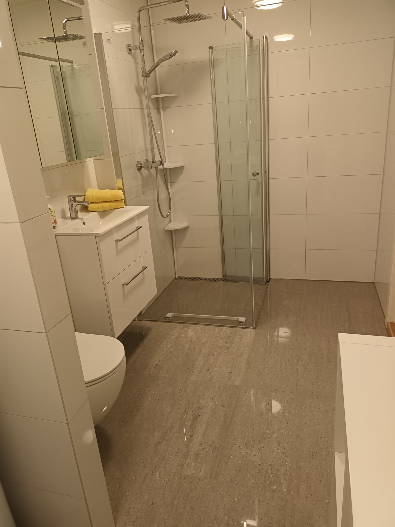 Lekkert nyfliset bad med regnfalldusj ogfastmontert glassvegg, varmekabler på gulv Galleribilde