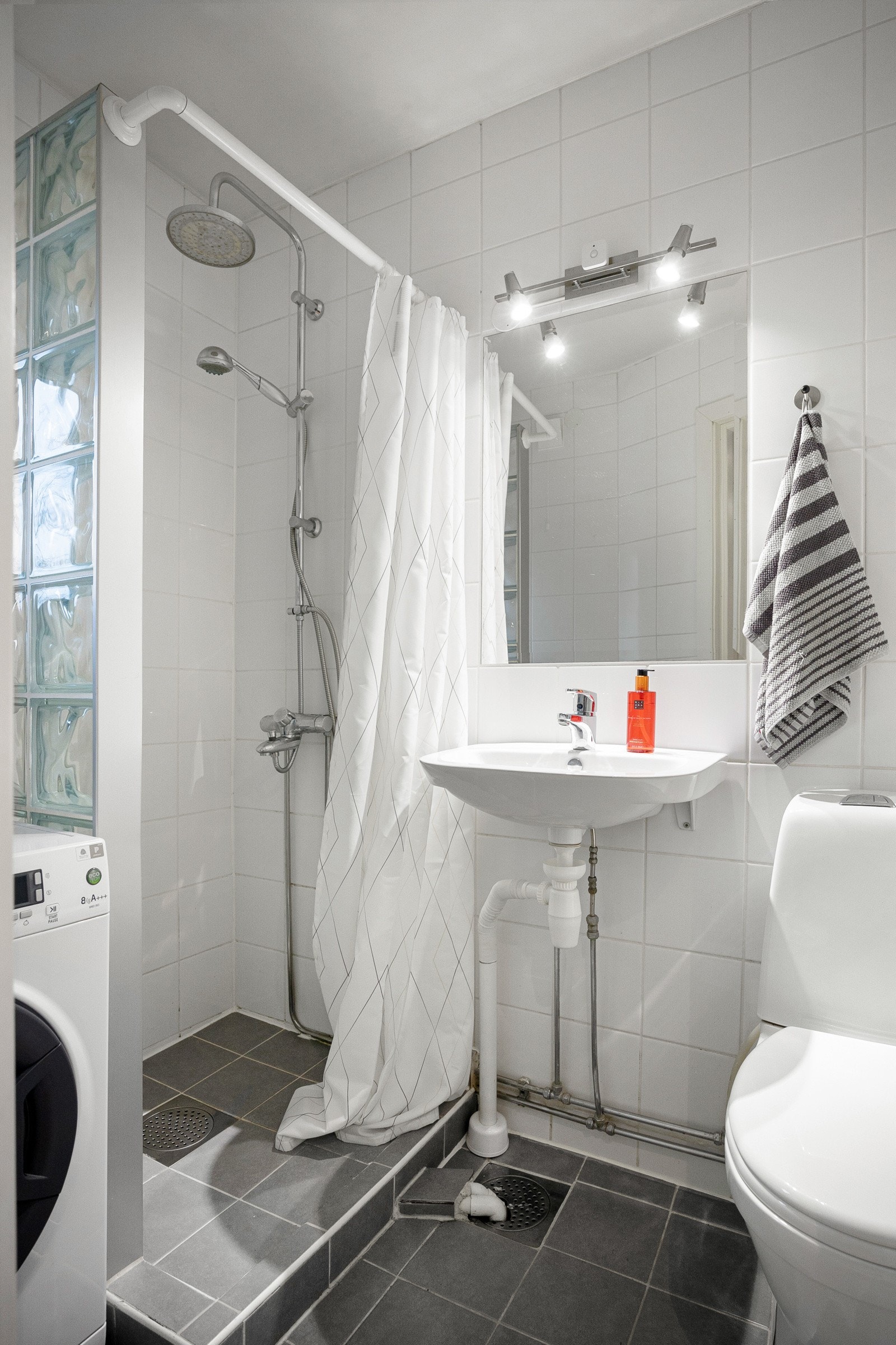 Flislagt baderom med dusjhjørne og gulvstående toalett. Galleribilde