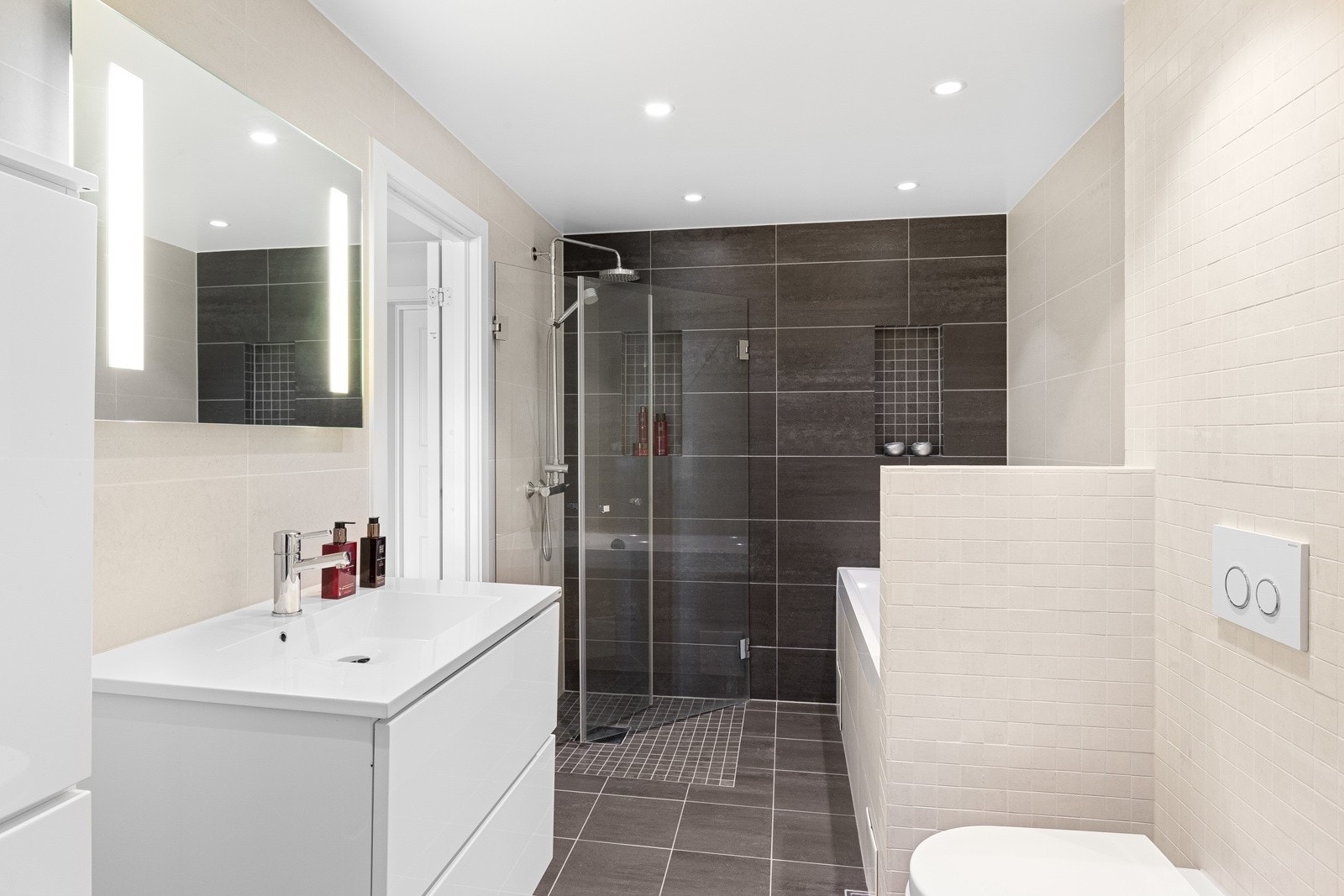 Innholdsrikt og godt utnyttet bad med flislagte gulv og vegger, varmekabler og pen innredning. Galleribilde