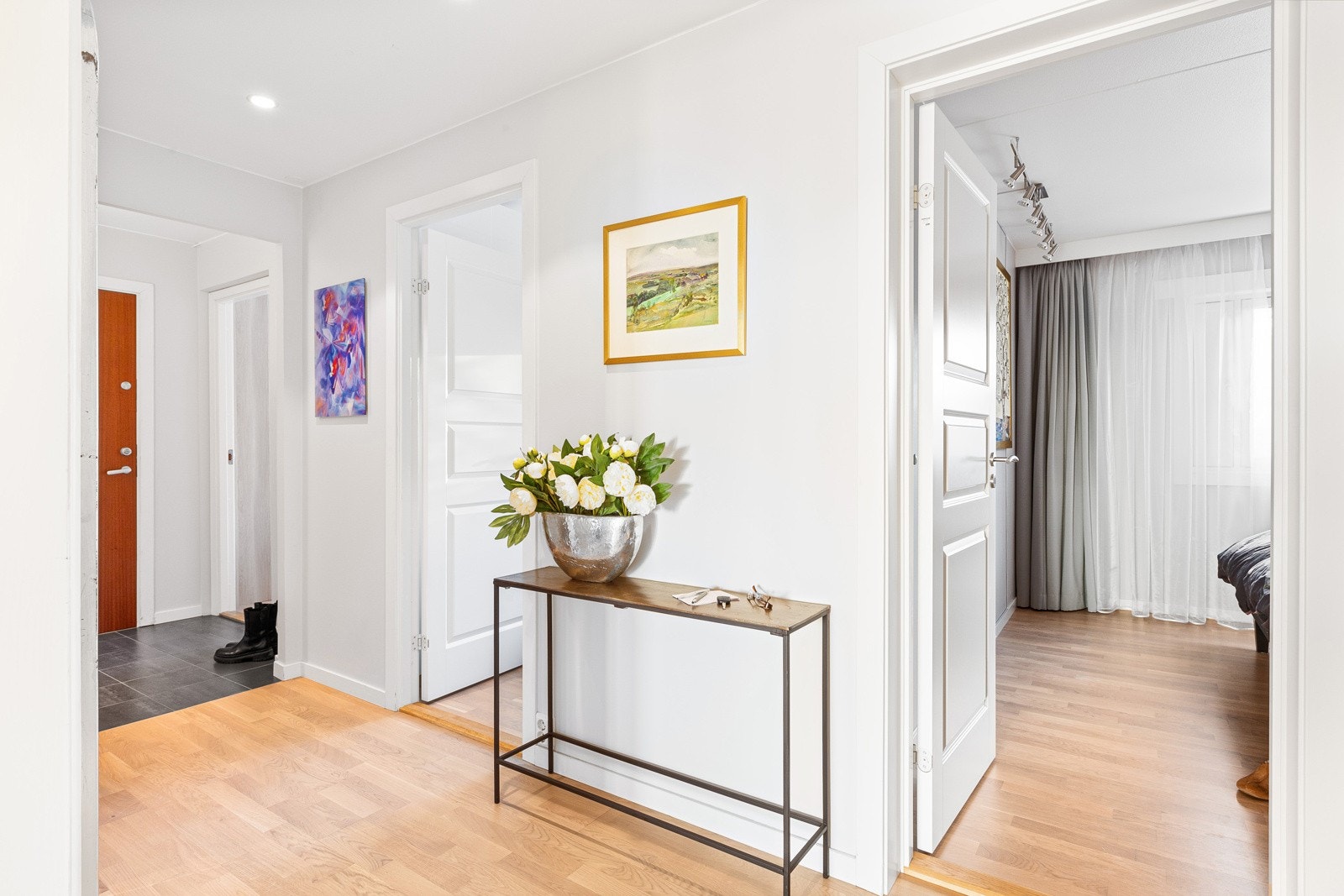 Hallen er lys og innbydende og fungerer som leilighetens knutepunkt. Galleribilde