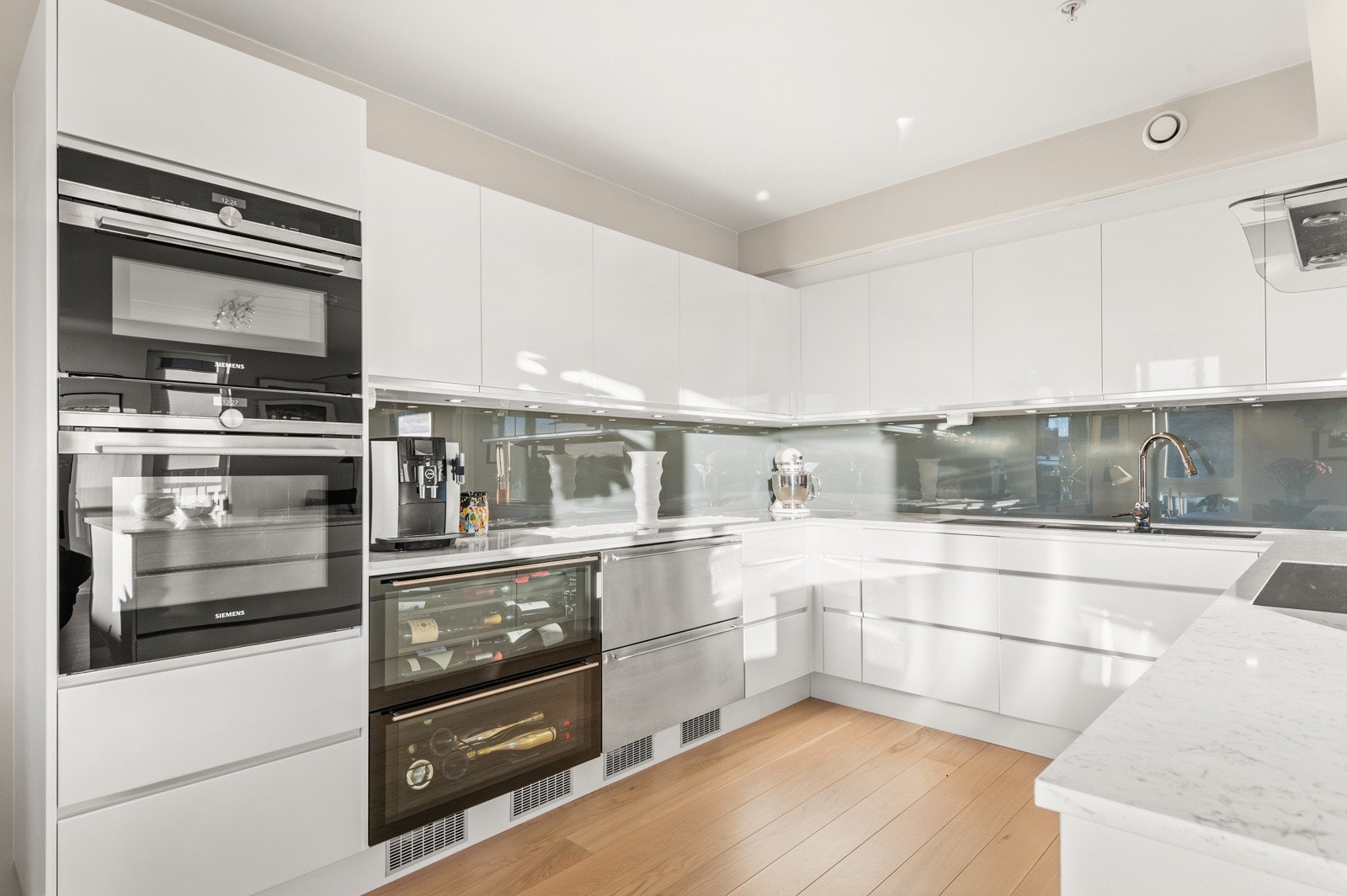 Innredning fra drømmekjøkken med hvite, slette fronter i høyglans og god skap- og benkeplass. Galleribilde