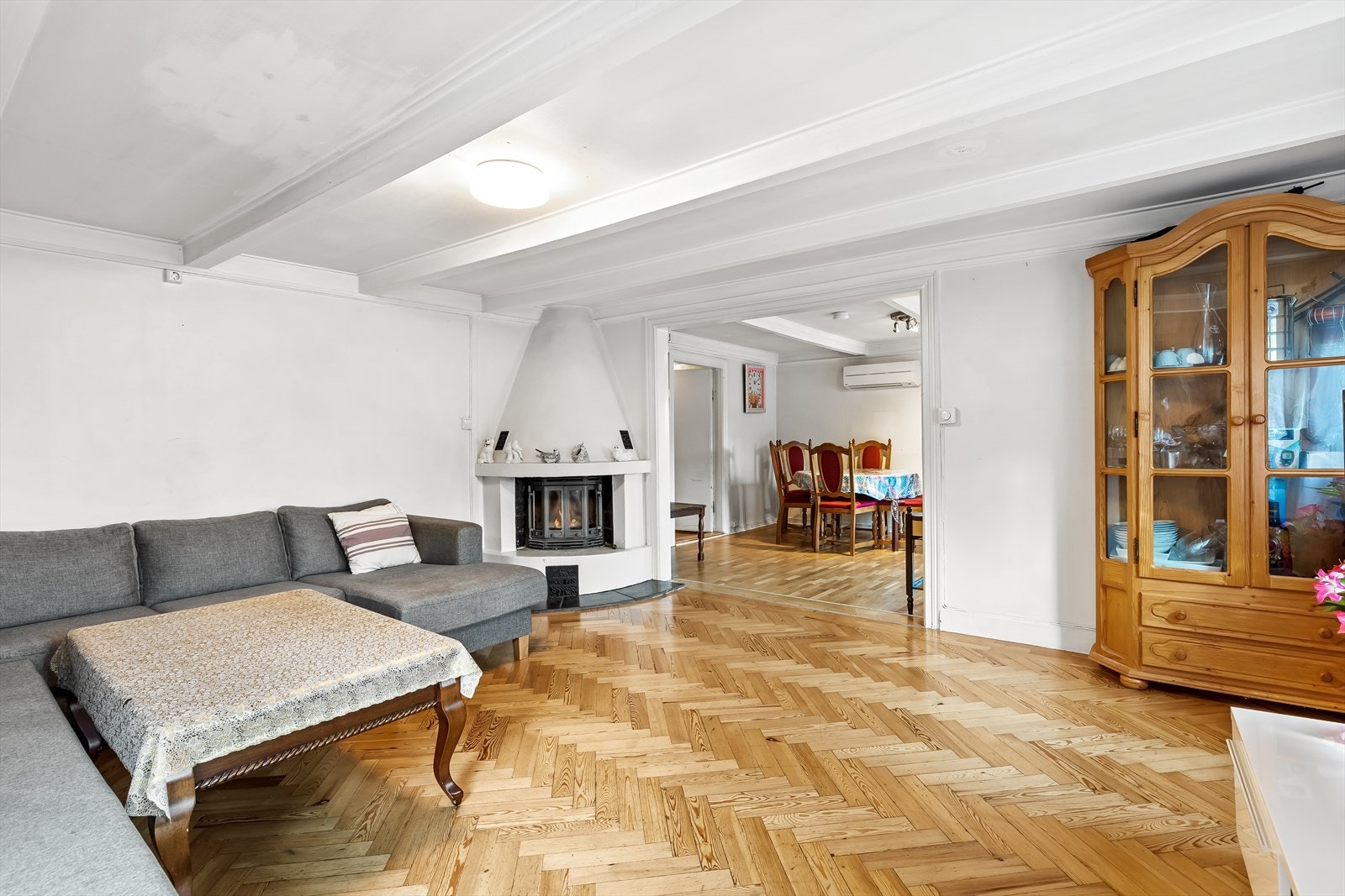 Rommet består av lakket furugulv i fiskebeinsmønster, hvitmalt tapet på vegger og hvite takplater med synlige bjelker Galleribilde