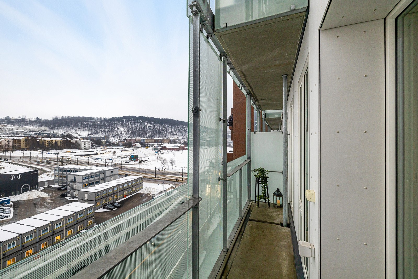 Balkongen har dekke gulv i betong og stålrekkverk kledd med glass som er glassfasaden til bygget. Galleribilde