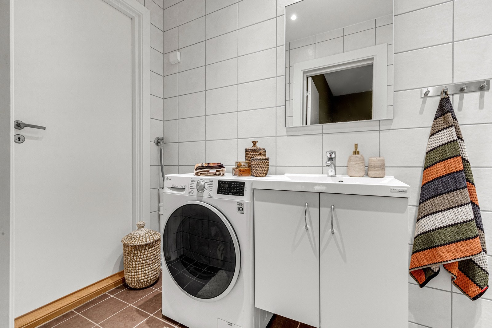 Flott flislagt baderom med vegghengt servant, dusjnisje med fronter i glass og opplegg for vaskemaskin. Galleribilde