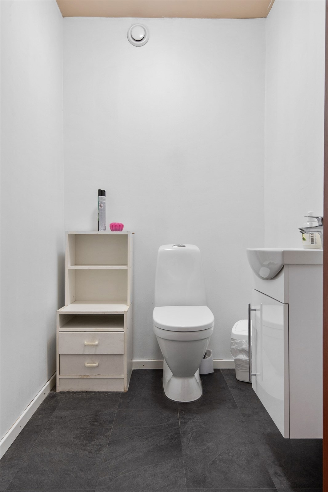 Separat WC, med gulvmontert klosett og servant med skapinnredning. Galleribilde