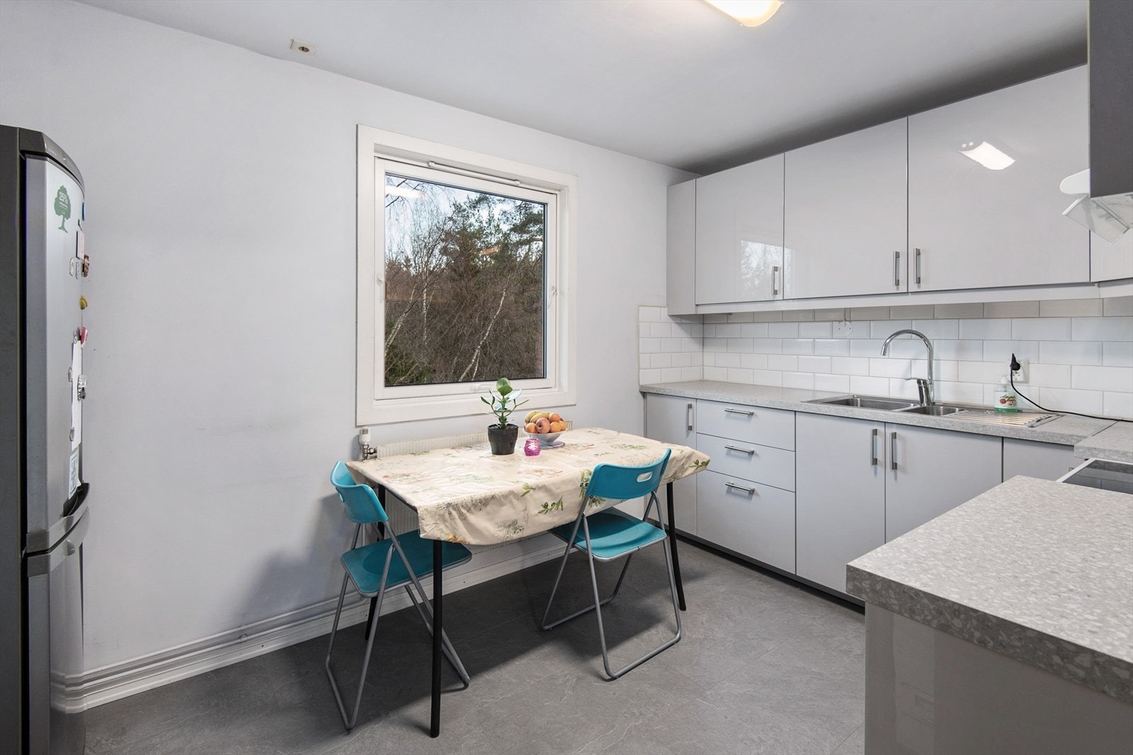 Kjøkken med glatte fronter i høyglans, Innredning fra 2020. Rustfri oppvaskkum med avrenningsplate og ventilator med filter. fliser mellom over- og underskap. Galleribilde