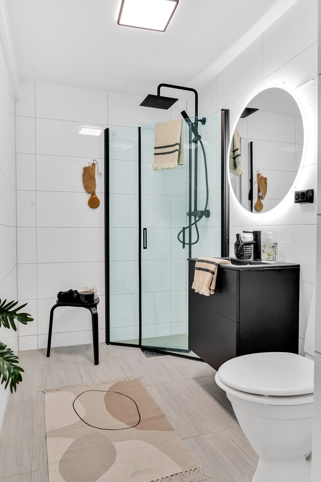 Badet er innredet med vegghengt toalett, dusjhjørne med innfellbare glassdører, servant med underskuffer og speil med integrert belysning Galleribilde