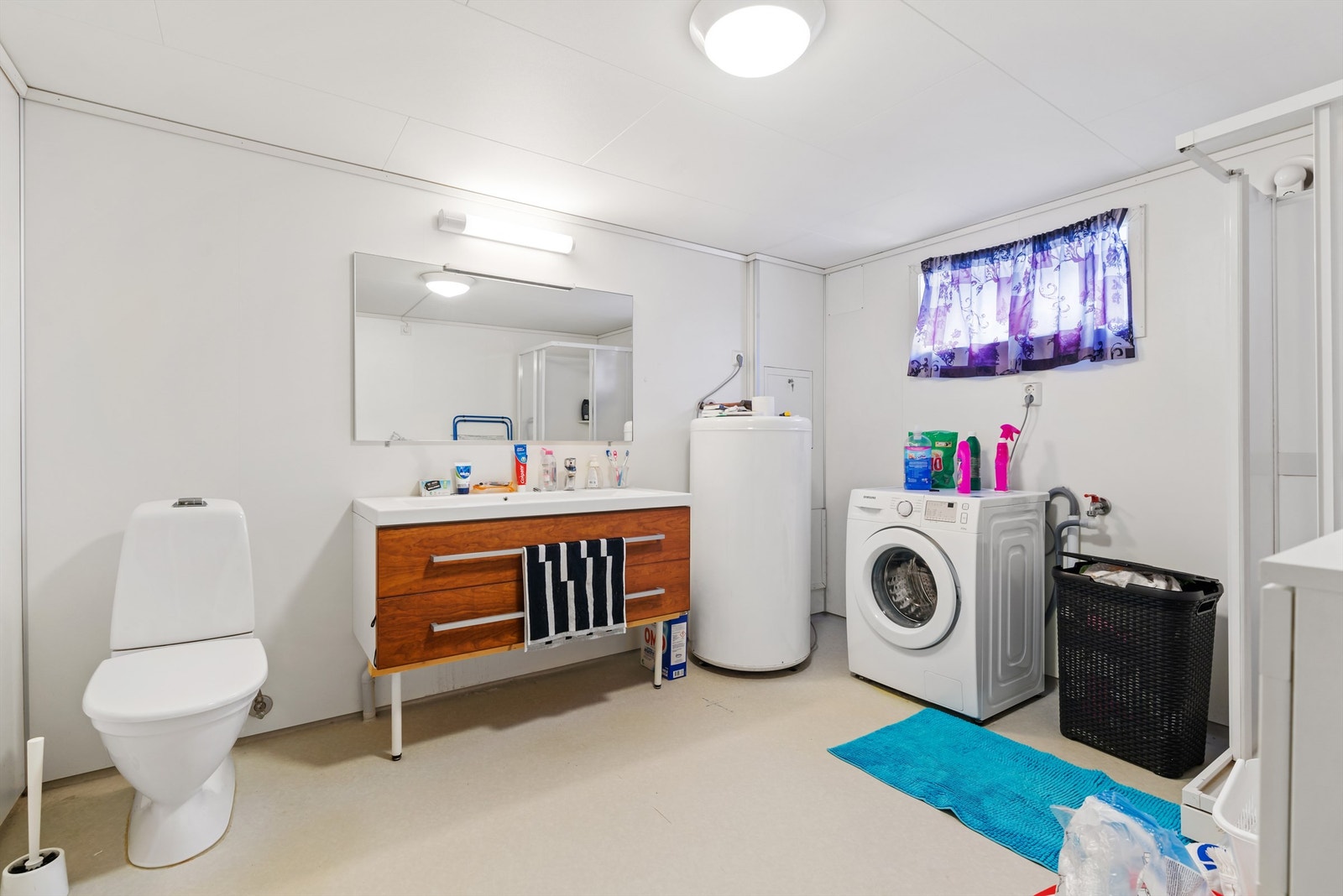 Bad/vaskerom av nyere dato. Belegg på gulv og våtromsplater vegg. Badet er utstyrt med dusjkabinett, vask med dobbelservant, varmtvannsbereder fra 2005 og opplegg til vaskemaskin. Varmekabler i gulv. Galleribilde