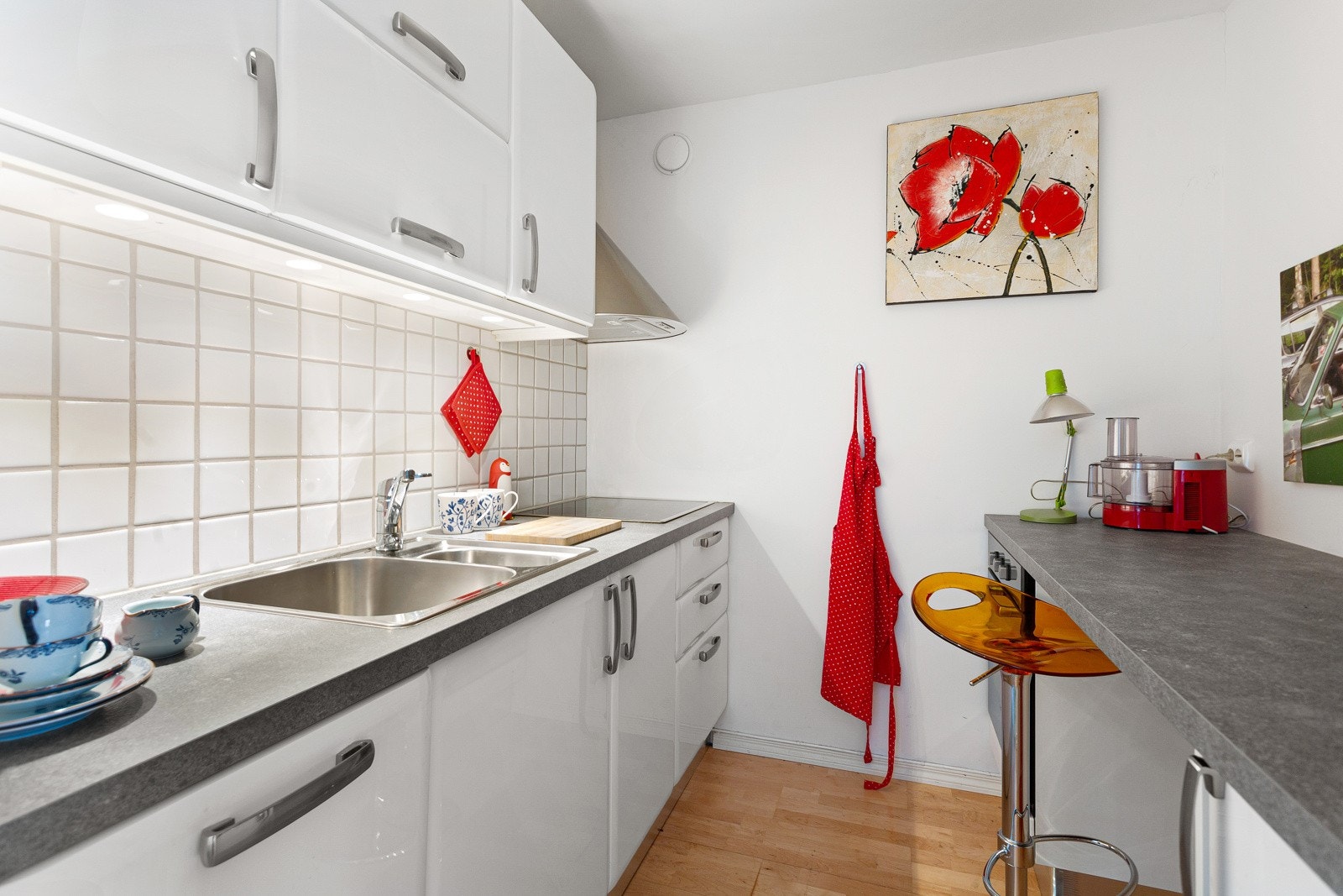 Innredningen har fronter i hvit høyglans, ledbelysning under overskap og folierte benkeplater med nedfelt kum i rustfritt stål Galleribilde