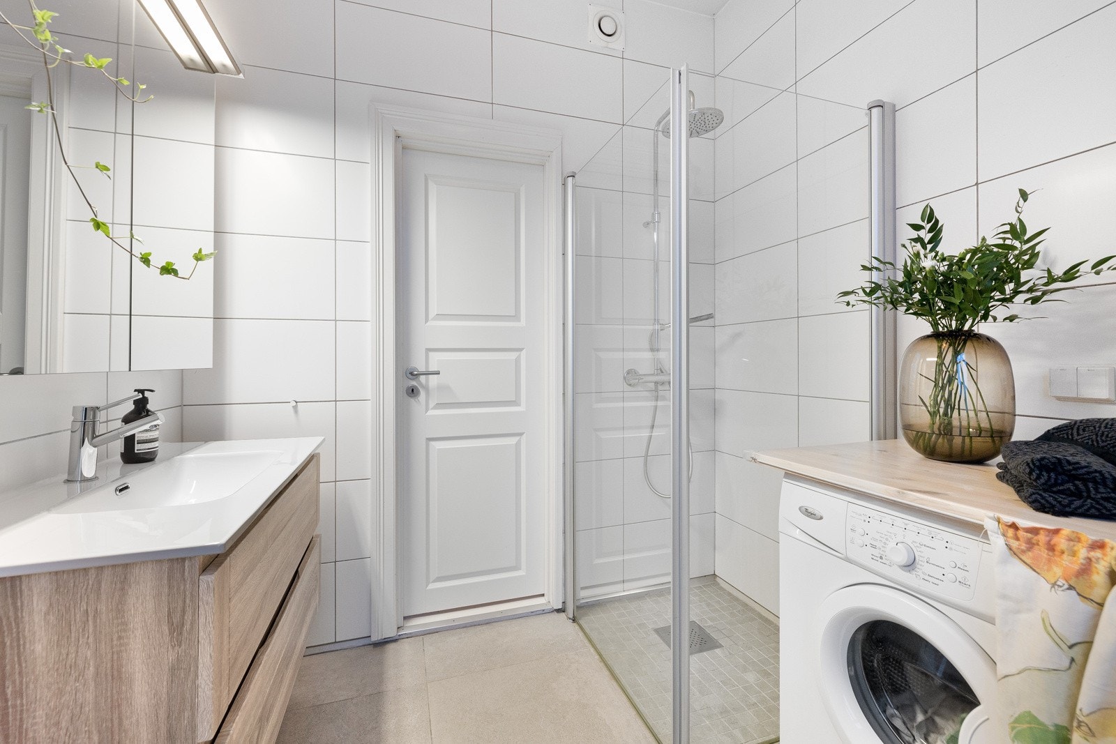 Baderomsinnredningen består av servant med underskap, overskap med speildører og lys, frittstående toalett, dusjhjørne med svingbare dører og opplegg for vaskemaskin. Galleribilde