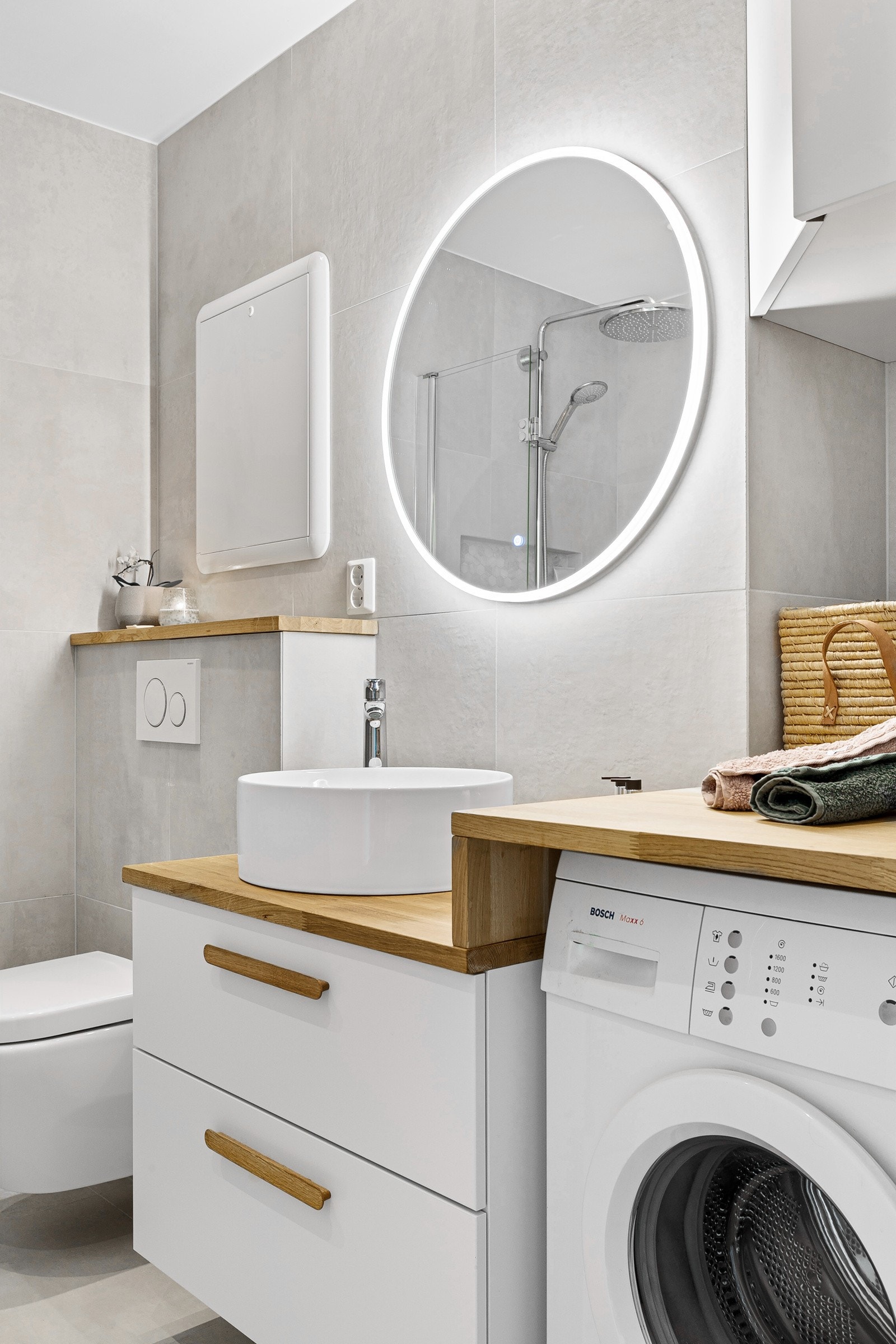 Heltre benkeplate står i fin kontrast til flisene. Fin servant og praktiske oppbevaringsskuffer. Benkeplaten er trukket videre langs veggen med opplegg for vaskemaskin under. Galleribilde