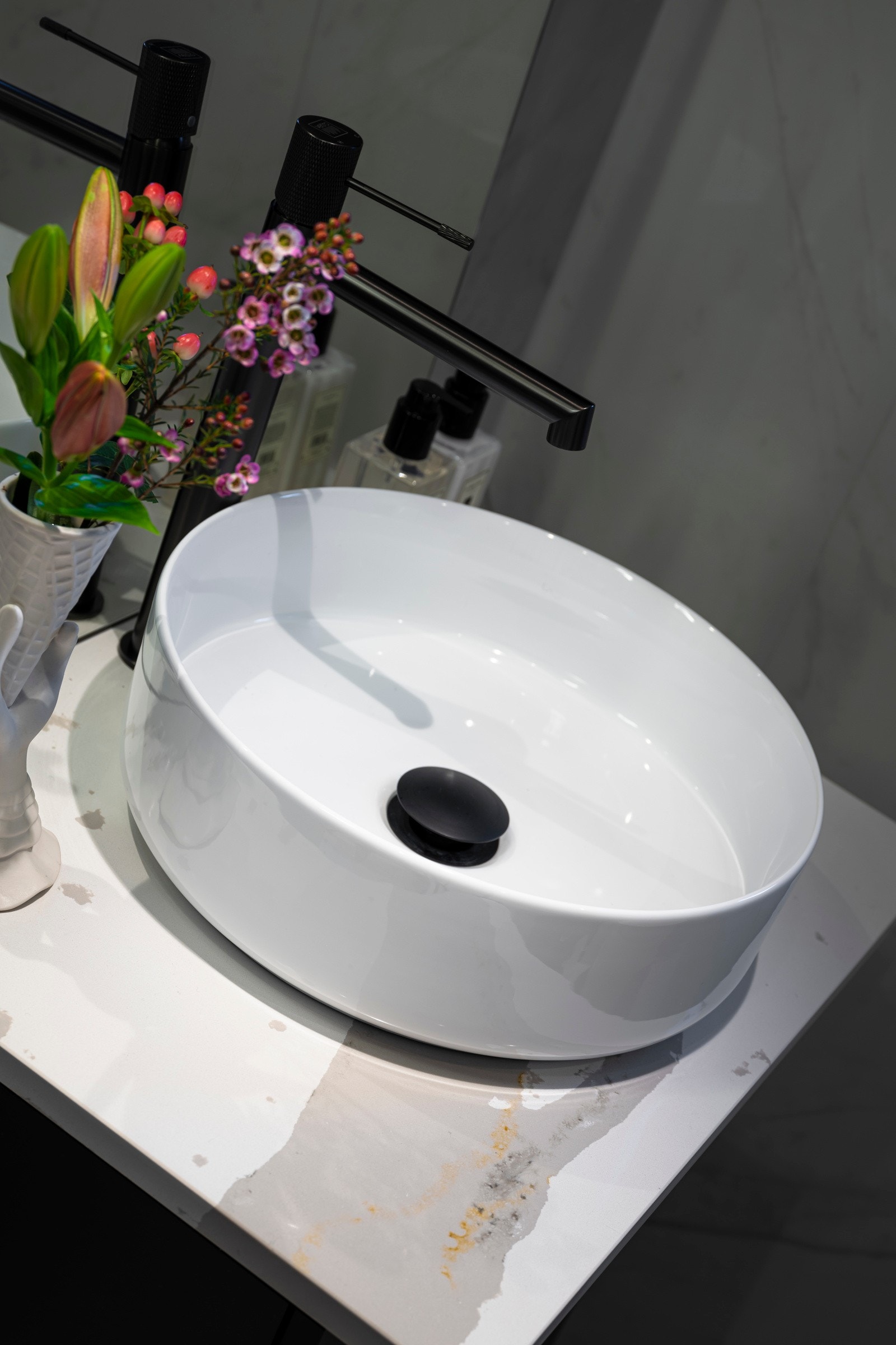 Servantskap med ovenpåliggende servant. Sorte detaljer på blandebatteri og bunnventil i servanten. Galleribilde