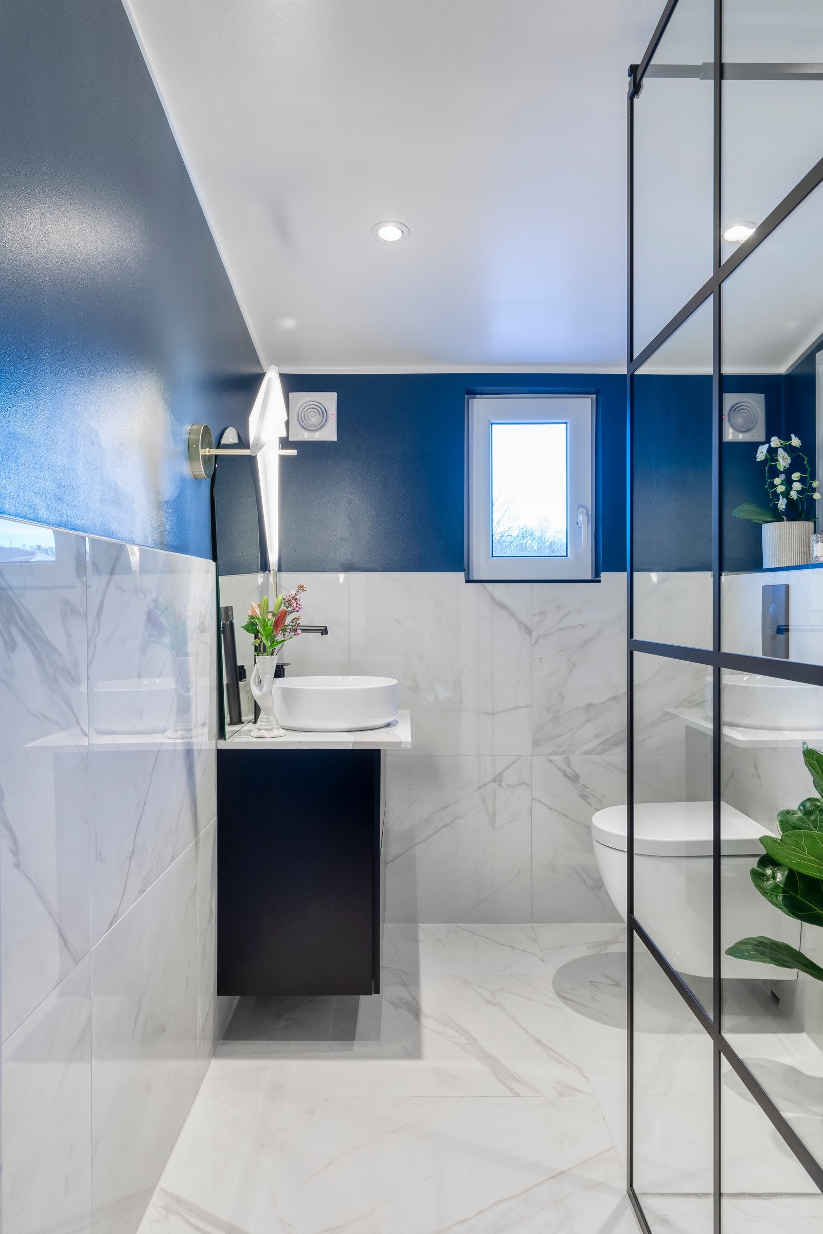 Badet har et moderne og lekkert preg med storformat fliser med flott design. Det er like fliser på gulv og vegg till brystning og malte flater for å få frem en fin kontrast. Galleribilde