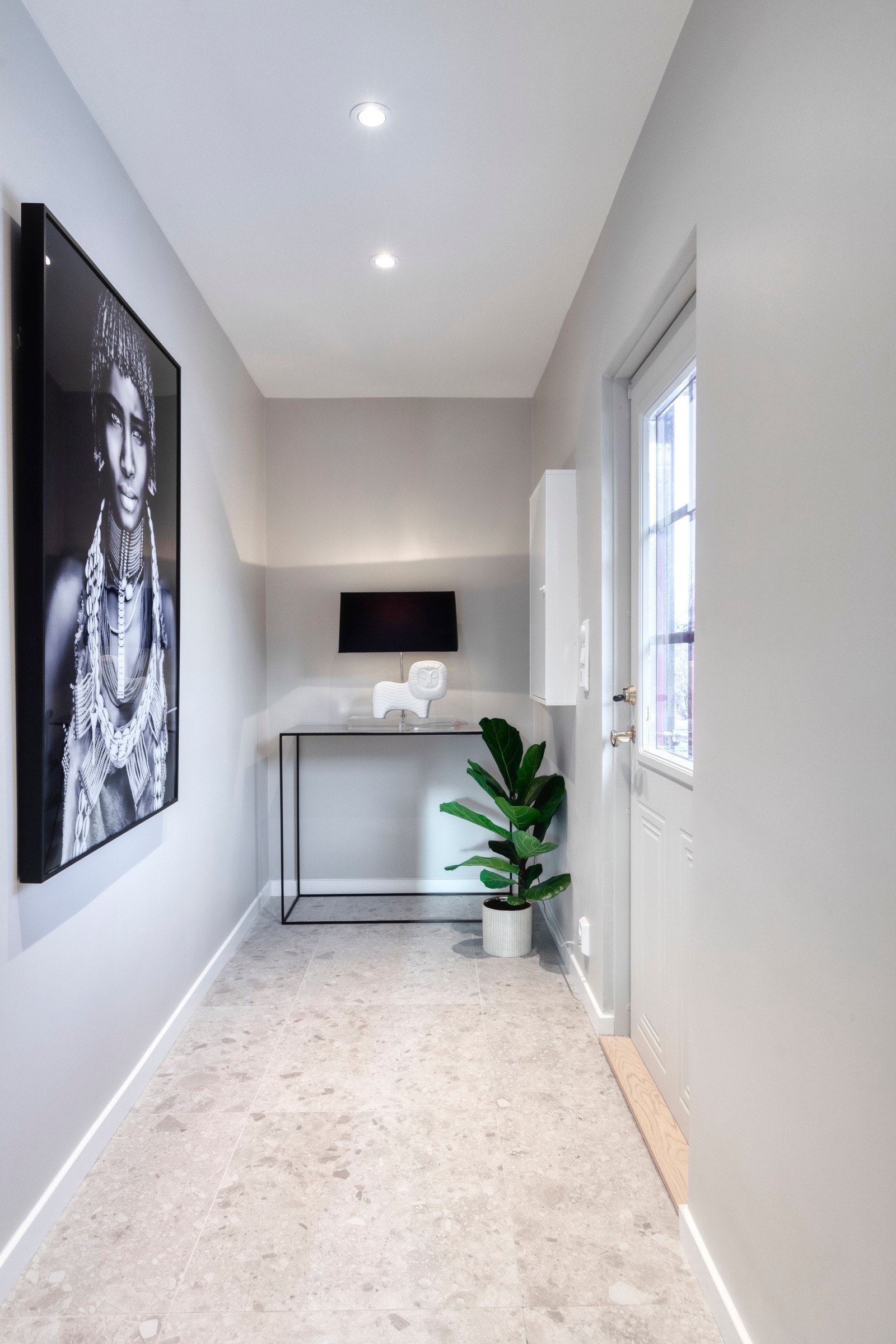 Lys og innbydende entré med flislagt gulv, delikat veggfarge og himling med downlights. Galleribilde