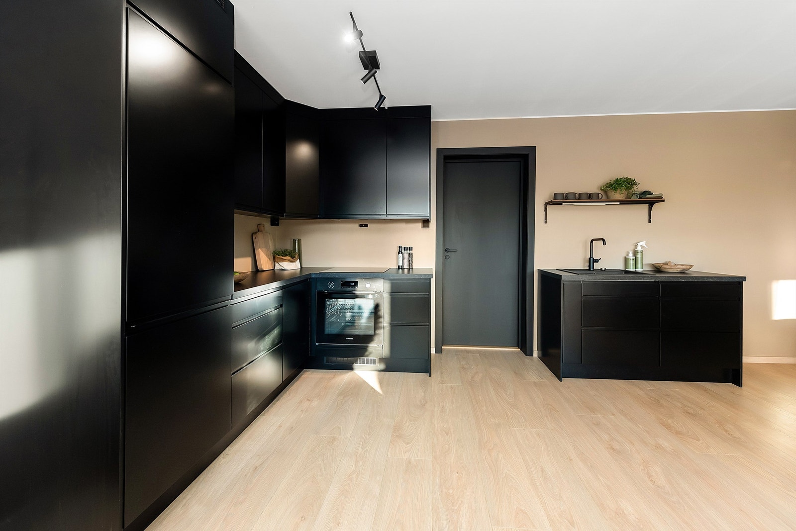 Det sorte kjøkkenet utgjør en flott kontrast til de ellers nøytrale overflatevalgene Galleribilde