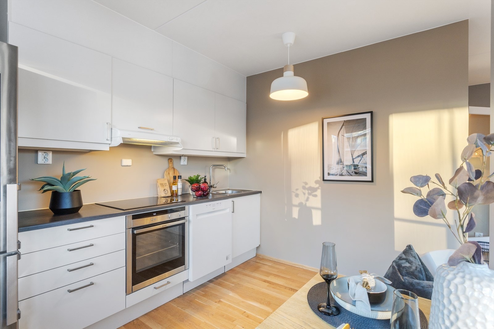 Kjøkkeninnredning type Sigdal med hvite glatte fronter, benkeplater i laminat, rustfri oppvaskkum, ventilator og integrerte hvitevarer Galleribilde