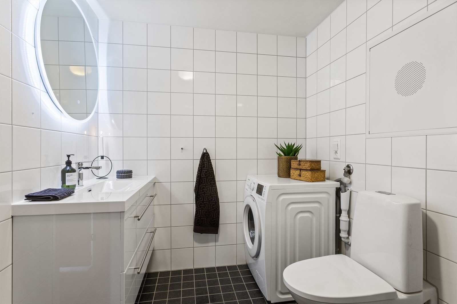 Helfliset baderom innredet med veggmonterte dusjvegger, dusj direkte på gulv med termostat batteri, veggmontert klosett, servant med skuffer og speil med belysning. Galleribilde