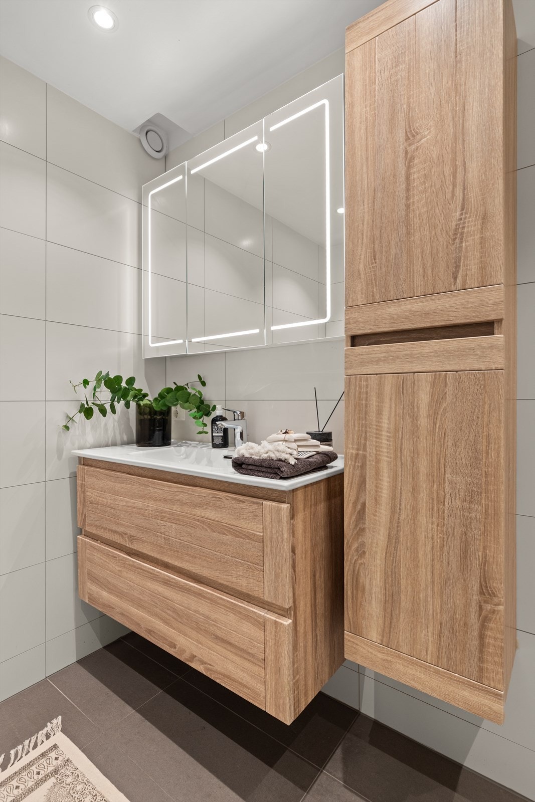 Lys innredning med flater i tre, lys i speilet på overskapet og innfelte downlights. Galleribilde