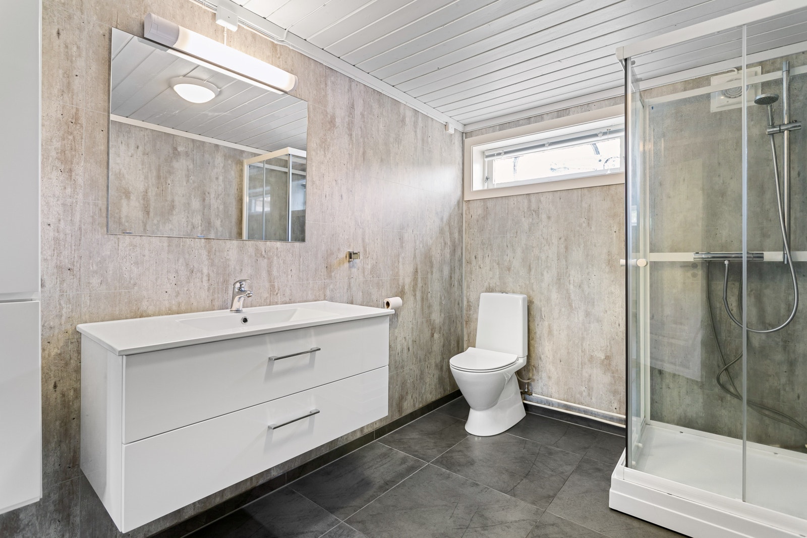 Bad innredet med servant på innredning, toalett og dusjkabinett. Galleribilde